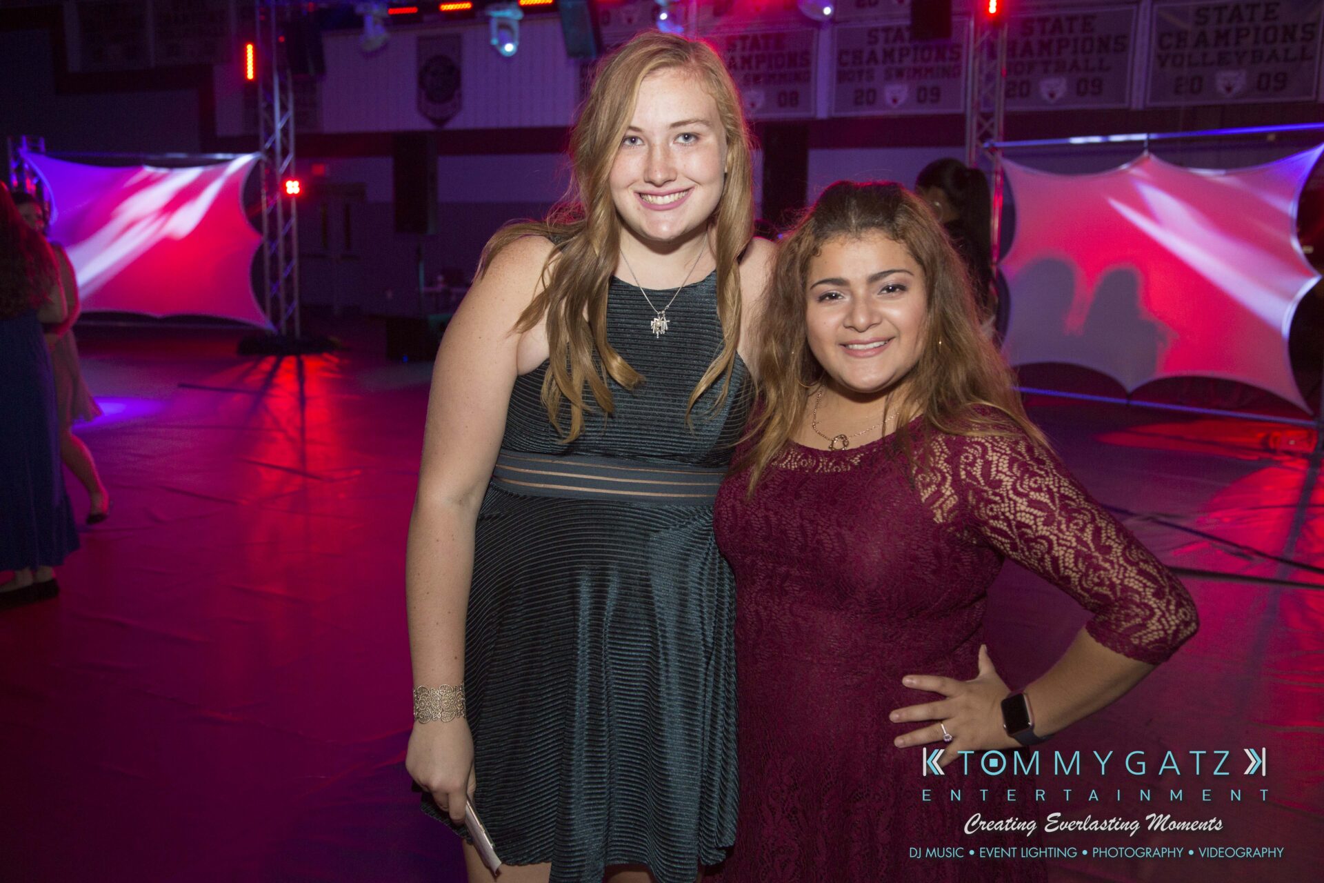Broadneck-HC-FINAL-2017-BLOG-LoRes-WM-22 - TOMMY GATZ ENTERTAINMENT Two people smiling at a party, standing on a dance floor with colorful lighting in the background.