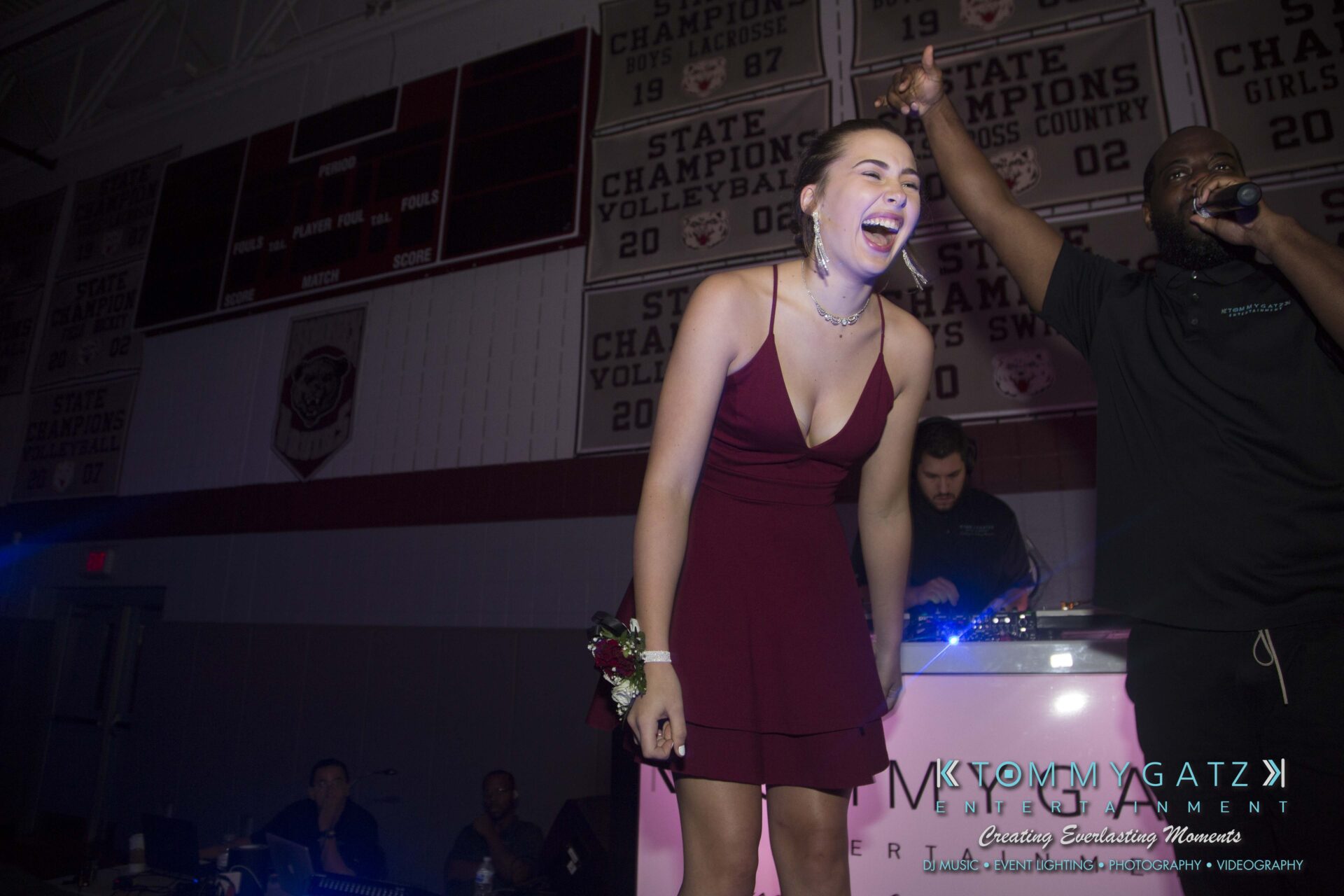 Broadneck-HC-FINAL-2017-BLOG-LoRes-WM-64 - TOMMY GATZ ENTERTAINMENT A woman in a burgundy dress laughs on stage with a microphone held by a man next to her.