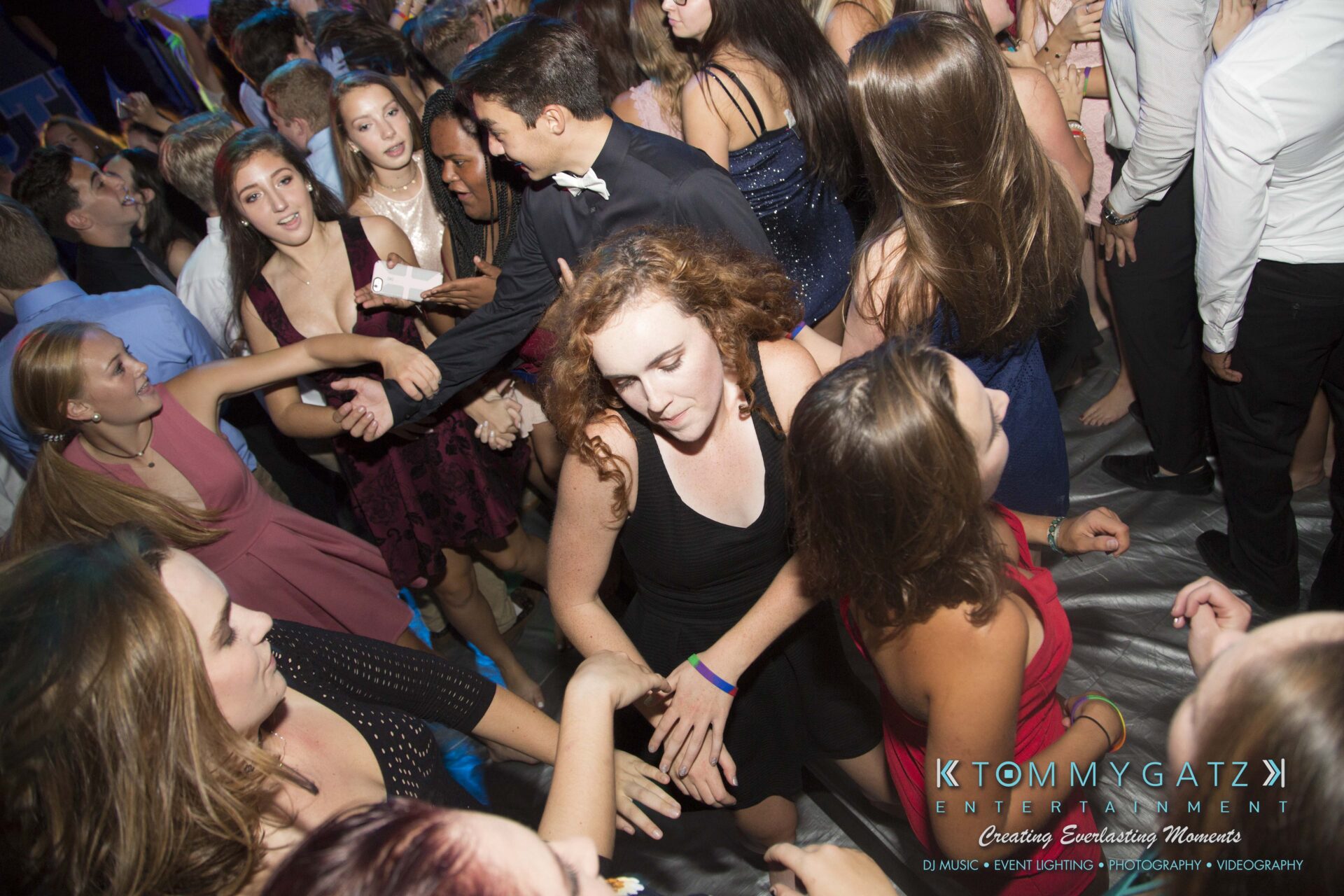 SR-HC-Dance-10717-BLOG-WM-47 - TOMMY GATZ ENTERTAINMENT A lively crowd of people, mostly in formal attire, are dancing closely in a dimly lit room.