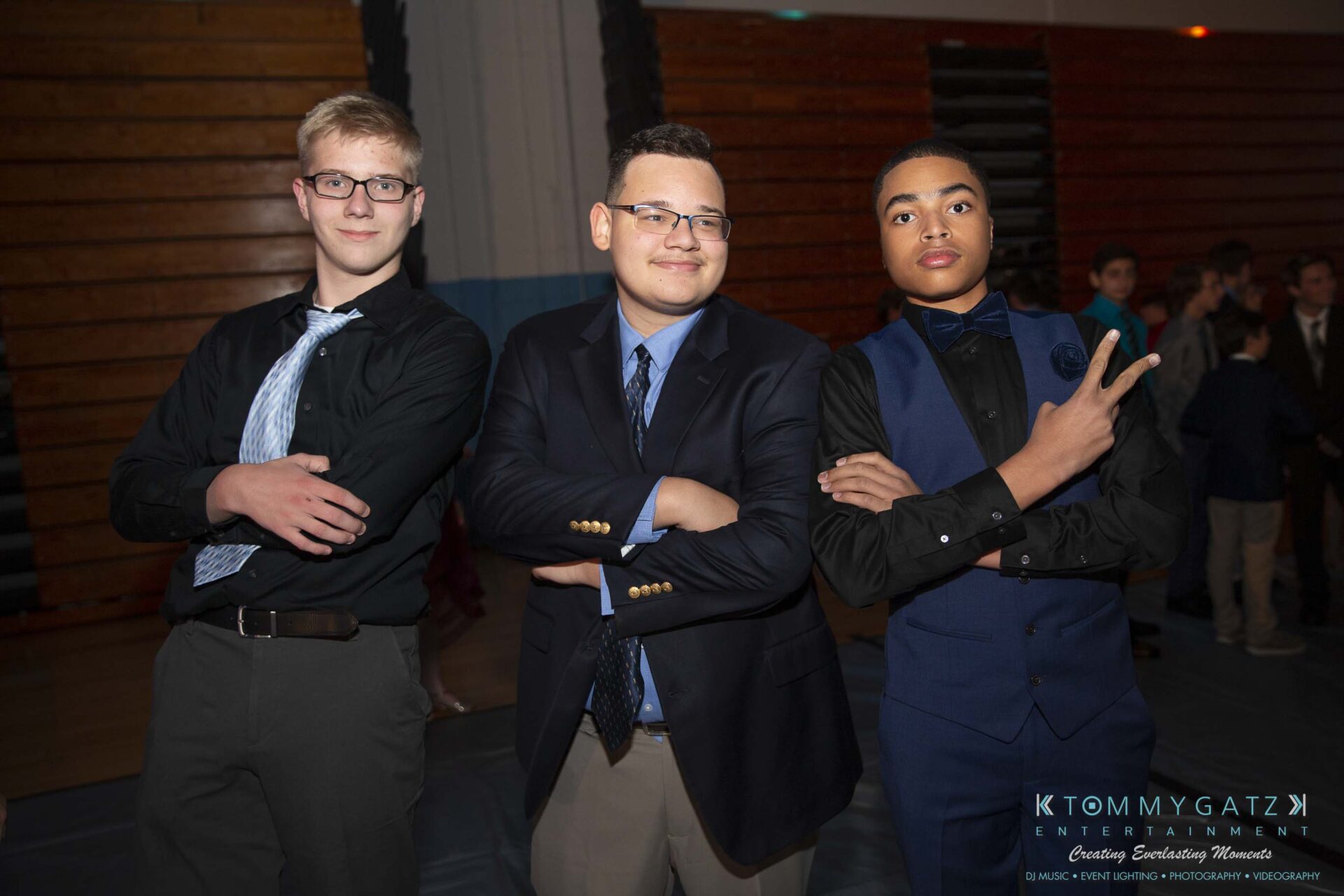 SR-Homecoming-102718-Carl-Low-Res-17 - TOMMY GATZ ENTERTAINMENT Three young men in formal attire pose confidently, standing side by side at an indoor event. One flashes a peace sign.