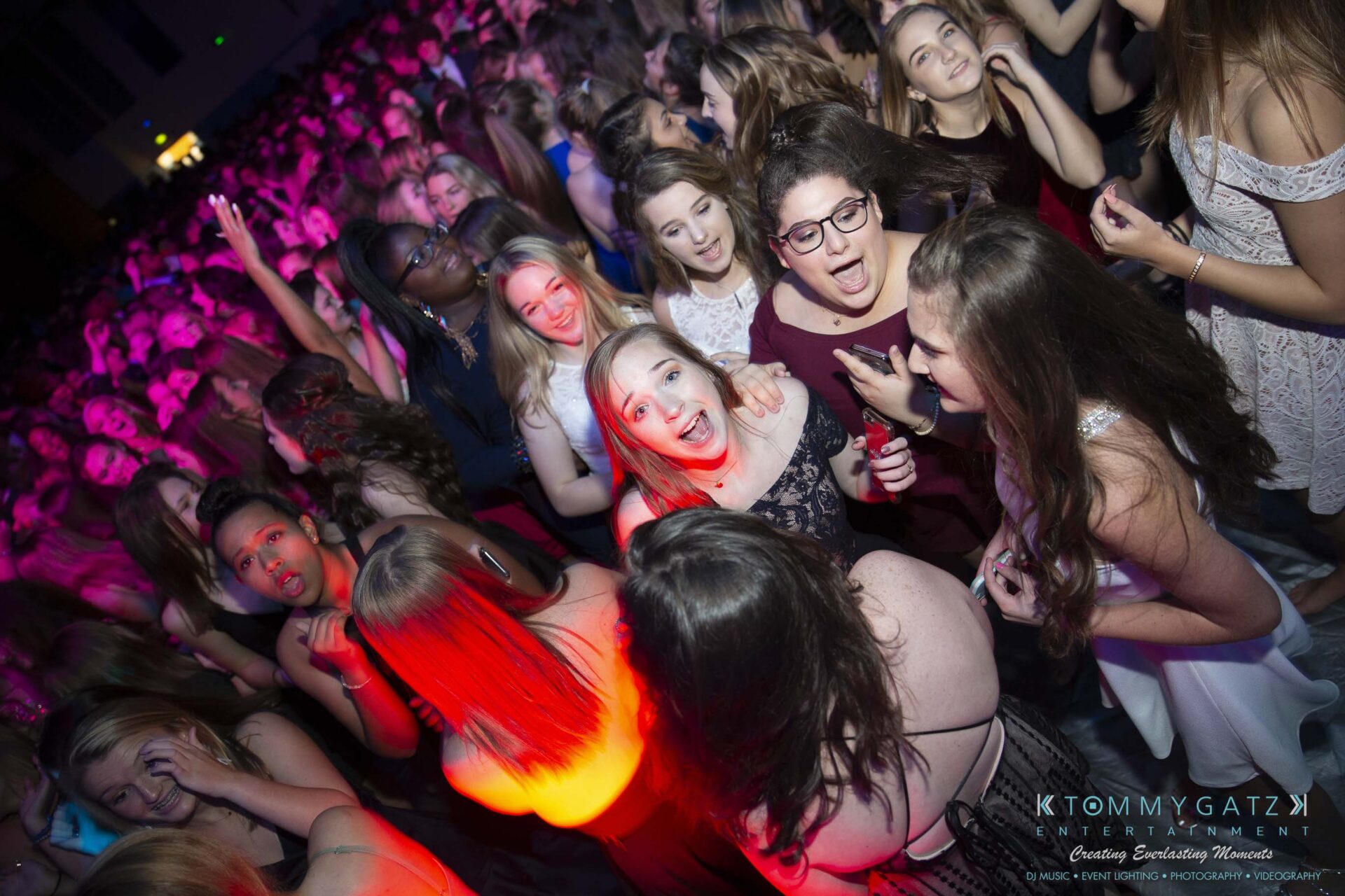 SR-Homecoming-102718-Carl-Low-Res-24 - TOMMY GATZ ENTERTAINMENT A group of people enjoying a crowded dance floor at an indoor event with purple and red lighting.