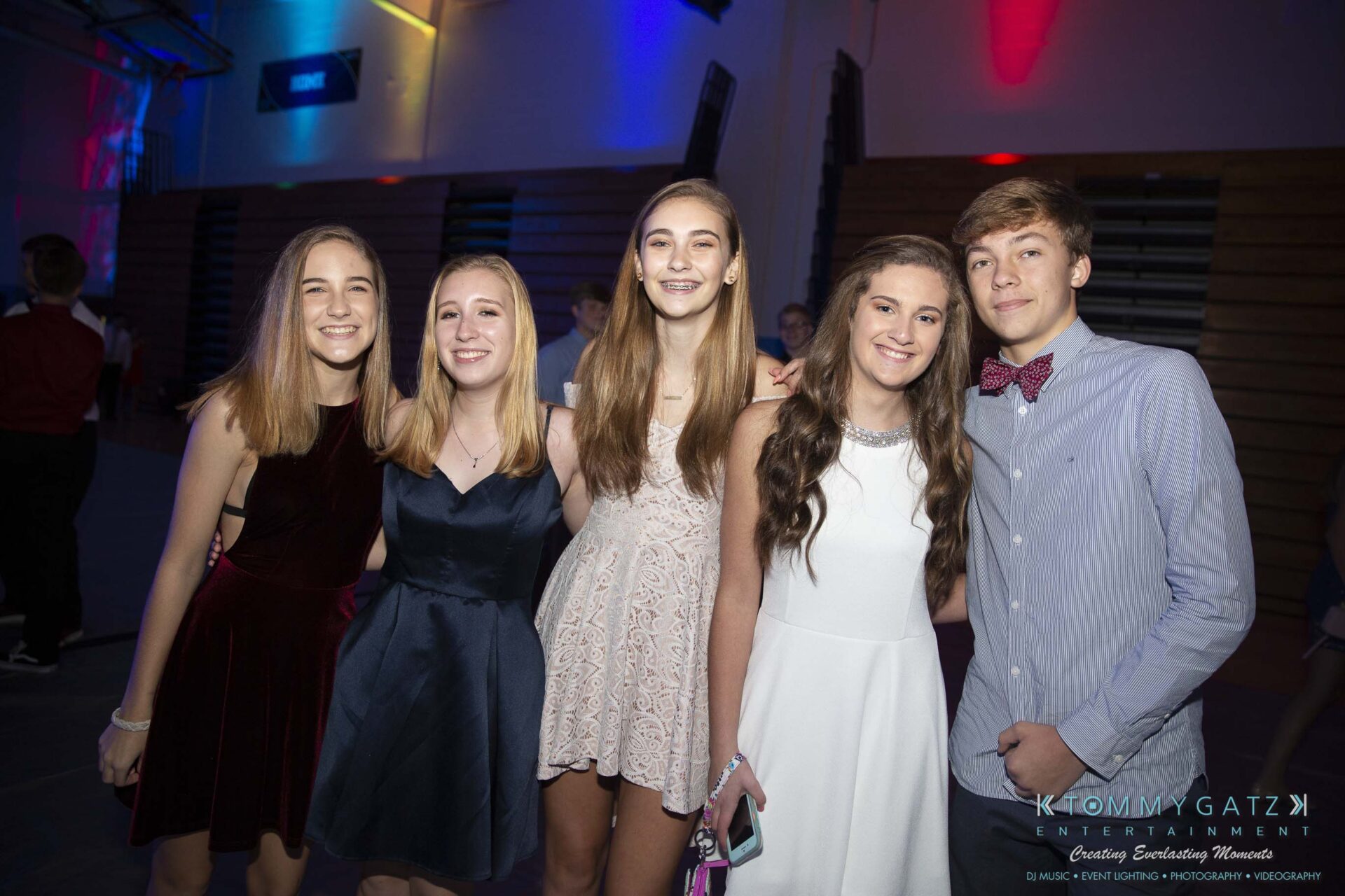 SR-Homecoming-102718-Carl-Low-Res-3 - TOMMY GATZ ENTERTAINMENT Five teenagers in formal attire at a social event, posing for a photo with smiles in a dimly lit room.