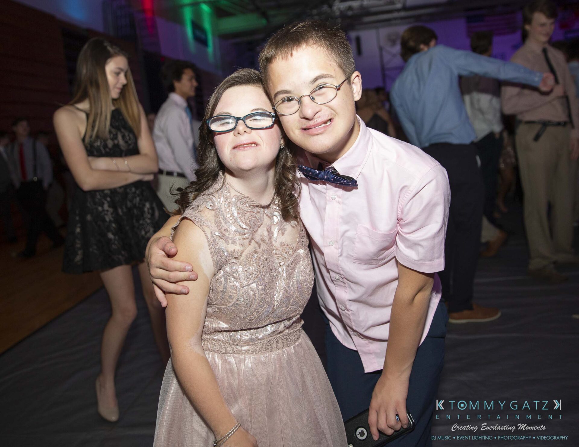 SR-Homecoming-102718-Carl-Low-Res-30 - TOMMY GATZ ENTERTAINMENT Two people smiling and embracing at a dance event. Other attendees are visible in the background.