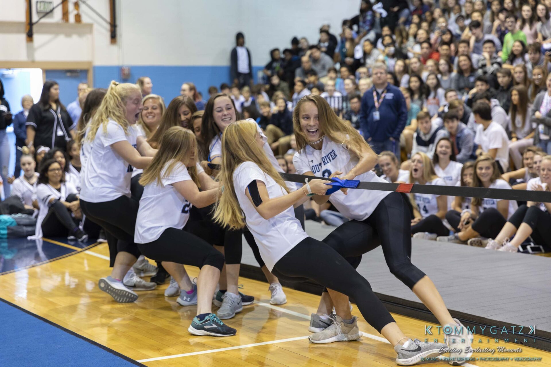 SR-Pep-Rally-102618-Carl-Low-Res-14 - TOMMY GATZ ENTERTAINMENT A group of students in matching shirts participate in a tug-of-war inside a gymnasium, with a large crowd watching in the background.