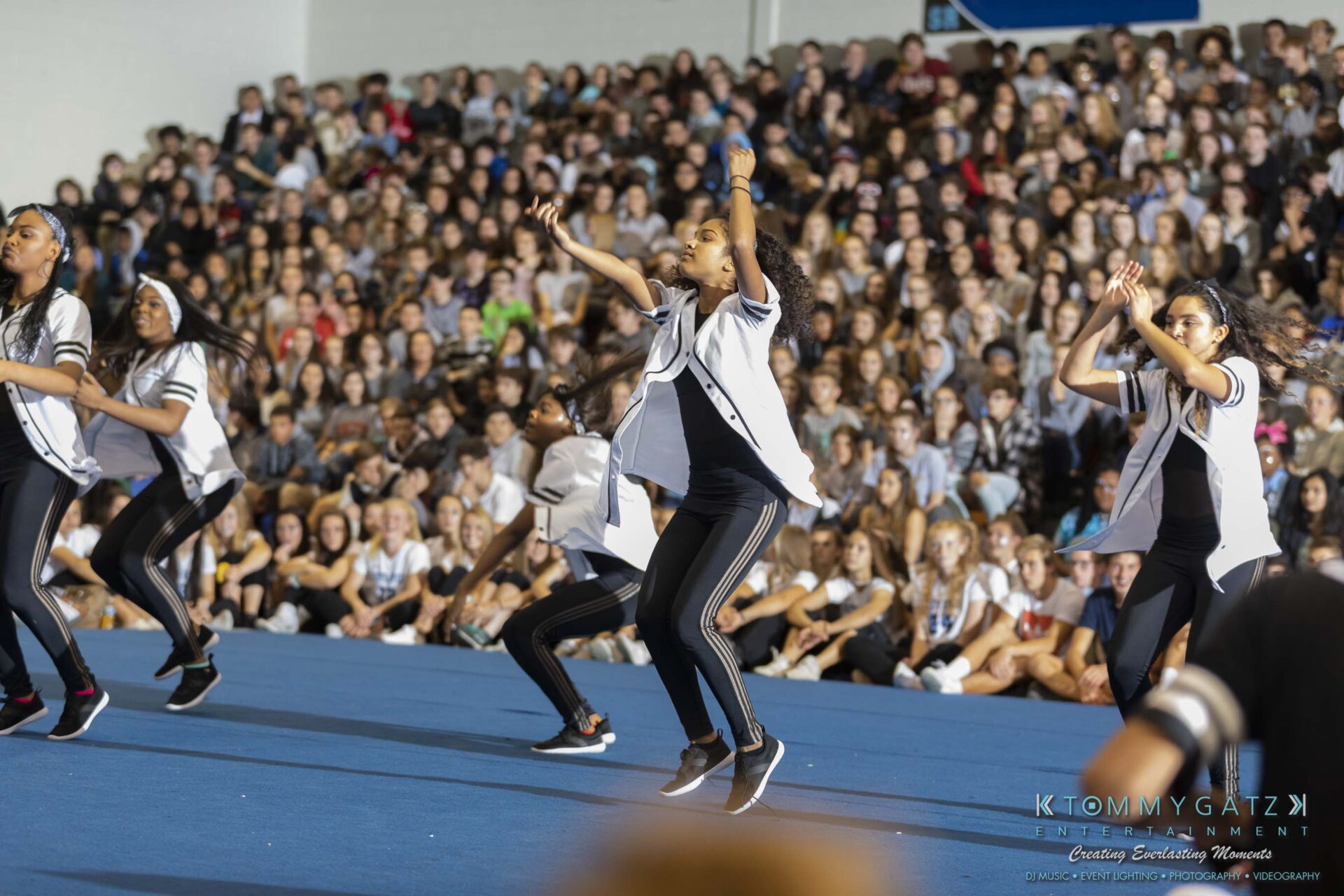 SR-Pep-Rally-102618-Carl-Low-Res-36 - TOMMY GATZ ENTERTAINMENT A dance team performs energetically on a gymnasium floor in front of a large, seated audience.