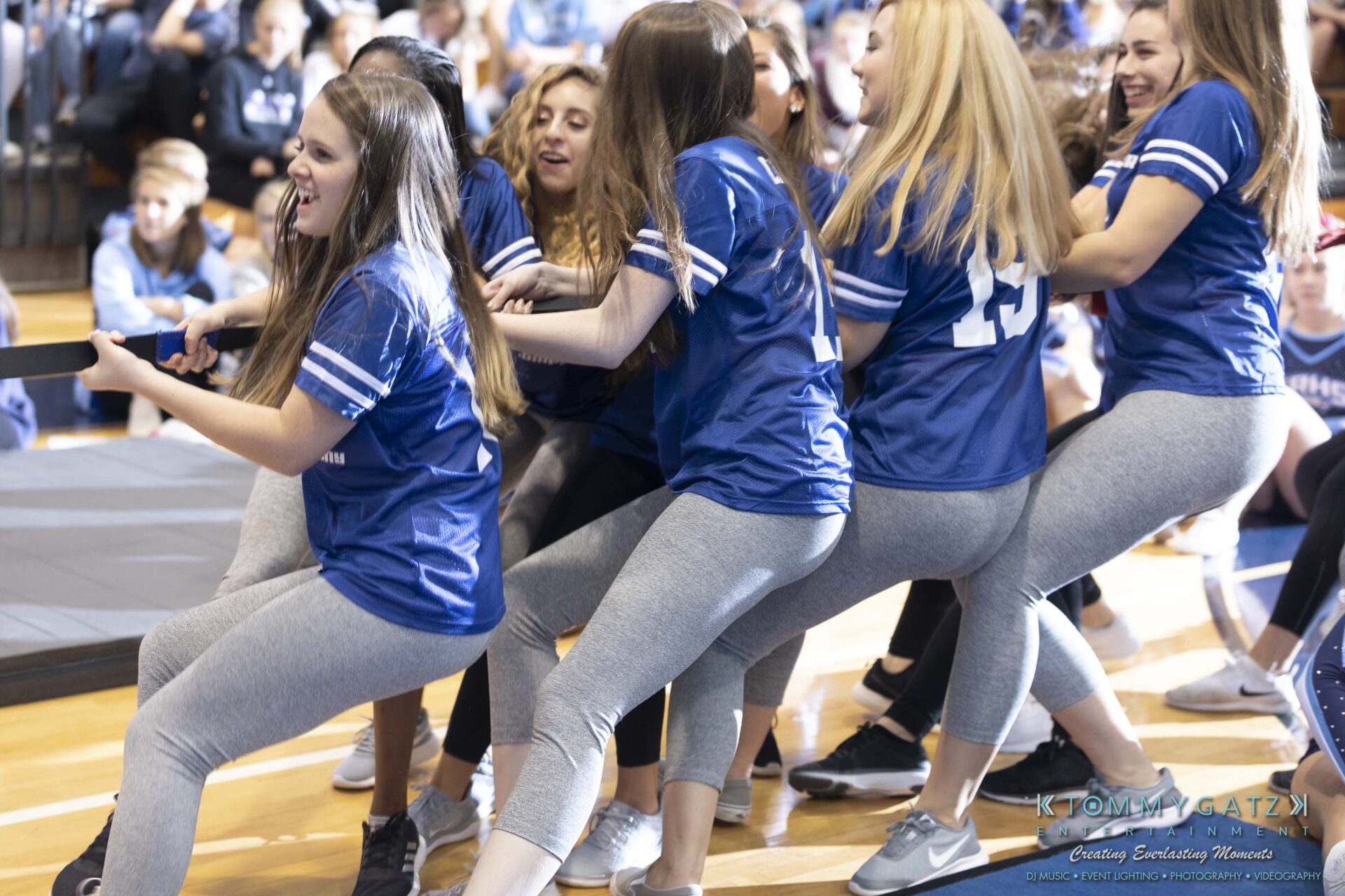 SR-Pep-Rally-102618-Carl-Low-Res-38 - TOMMY GATZ ENTERTAINMENT Group of young women in matching blue jerseys and gray leggings participate in a tug-of-war in a gymnasium.