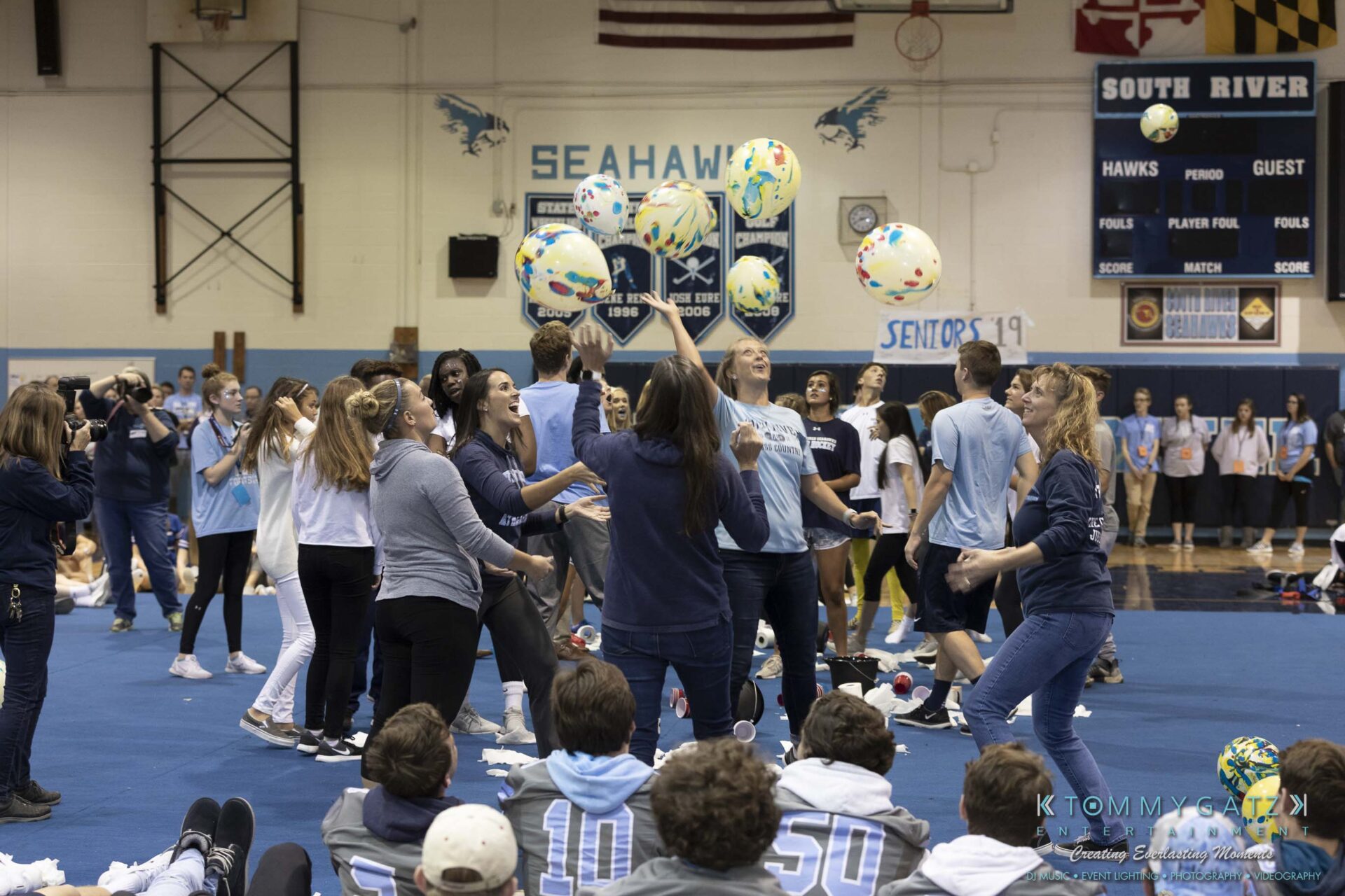 SR-Pep-Rally-102618-Carl-Low-Res-41 - TOMMY GATZ ENTERTAINMENT Group of people in a gym participating in an event, tossing beach balls. Banners and spectators are visible in the background.