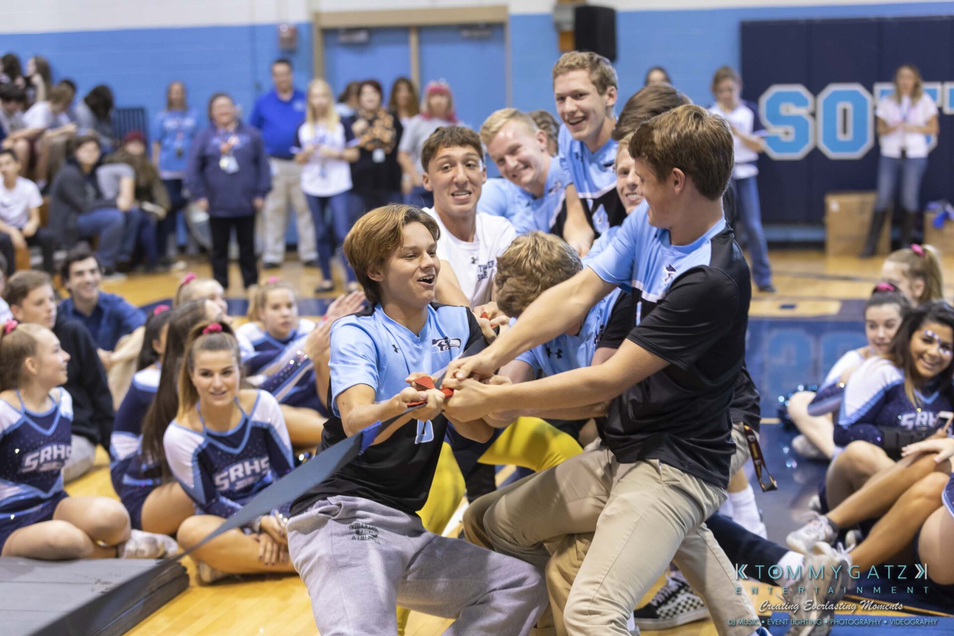 SR-Pep-Rally-102618-Carl-Low-Res-52 - TOMMY GATZ ENTERTAINMENT A group of people participate in a tug-of-war match indoors, with a crowd watching.