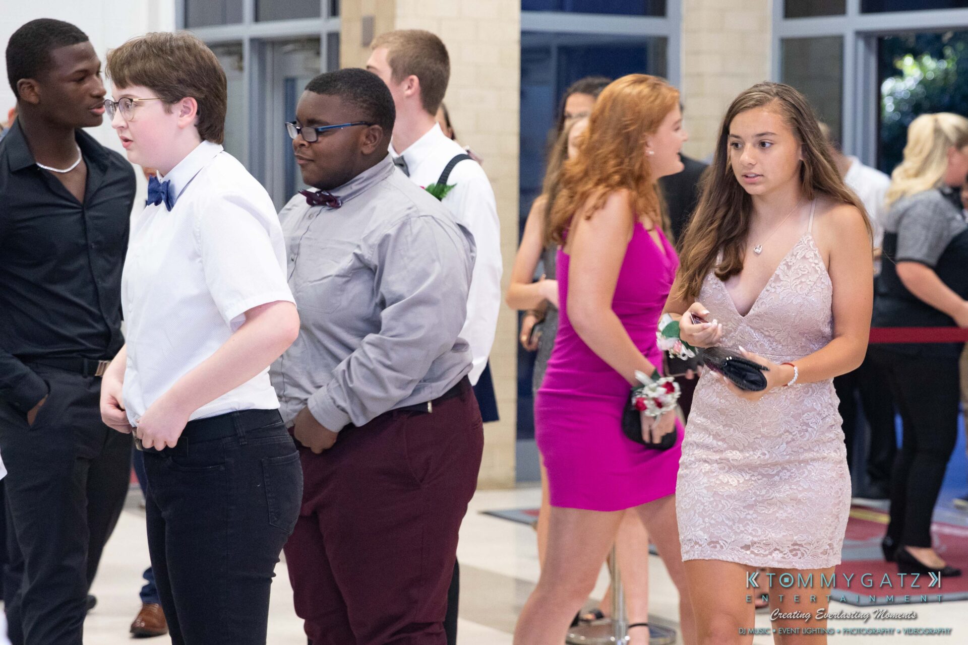 092819-Broadneck-Homecoming-Low-Res-WM-15-1 - TOMMY GATZ ENTERTAINMENT A group of young adults dressed formally, walking inside a building. Some wear suits, while others are in dresses, suggesting they are attending a special event.