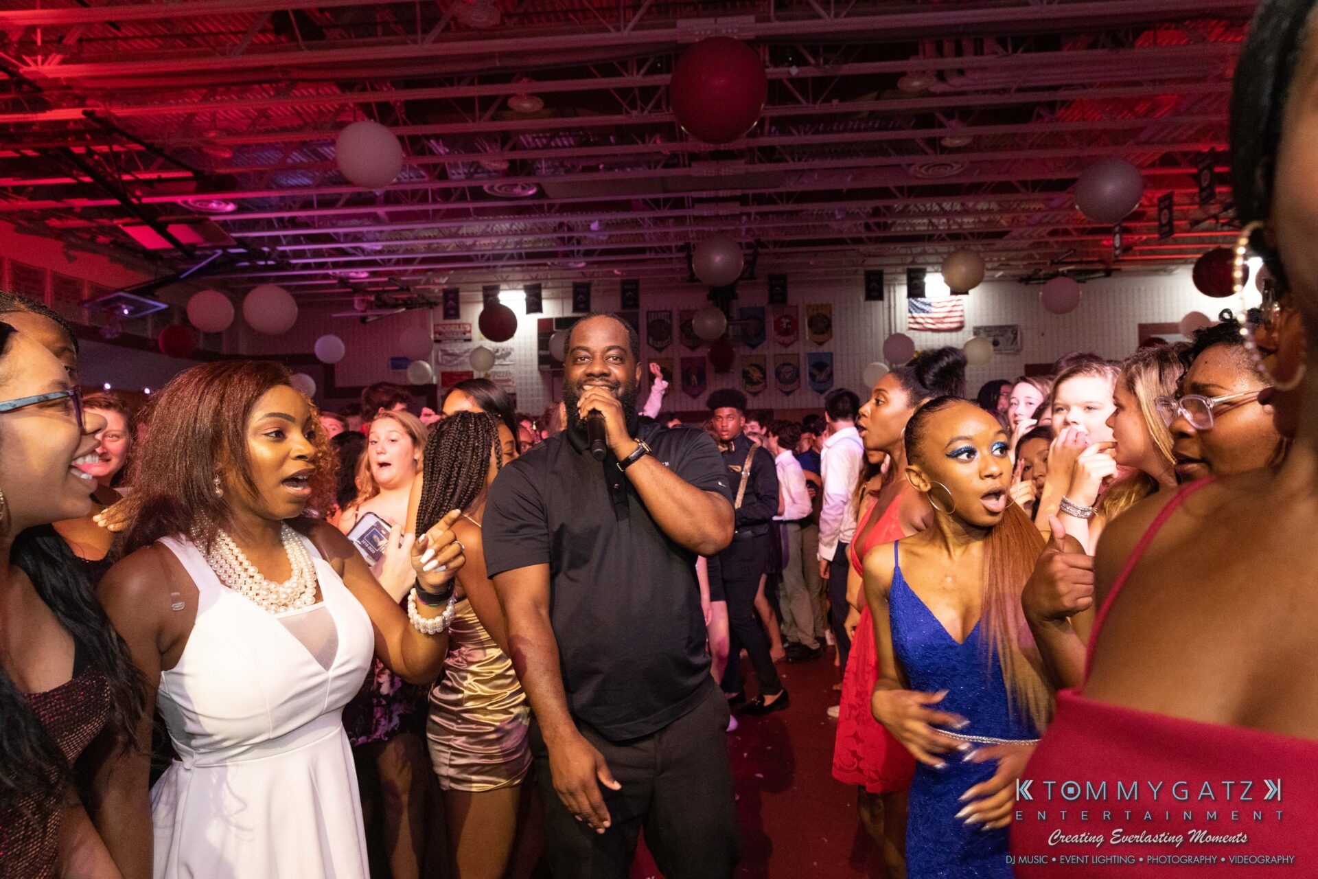 092819-Broadneck-Homecoming-Low-Res-WM-72 - TOMMY GATZ ENTERTAINMENT People dancing and socializing at a lively indoor event with colorful lights and decorations.