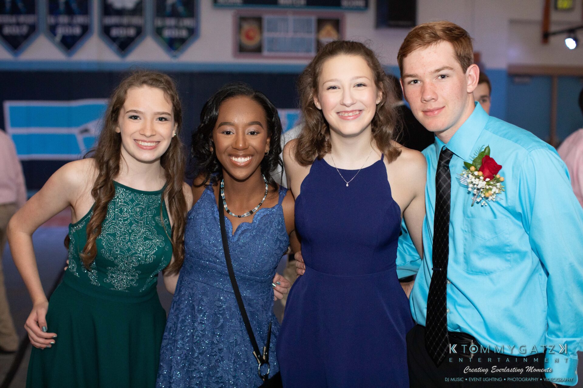 100519-South-River-HC-Dance-Low-Res-WM-22 - TOMMY GATZ ENTERTAINMENT Four young people dressed formally, smiling at the camera in a decorated indoor venue.