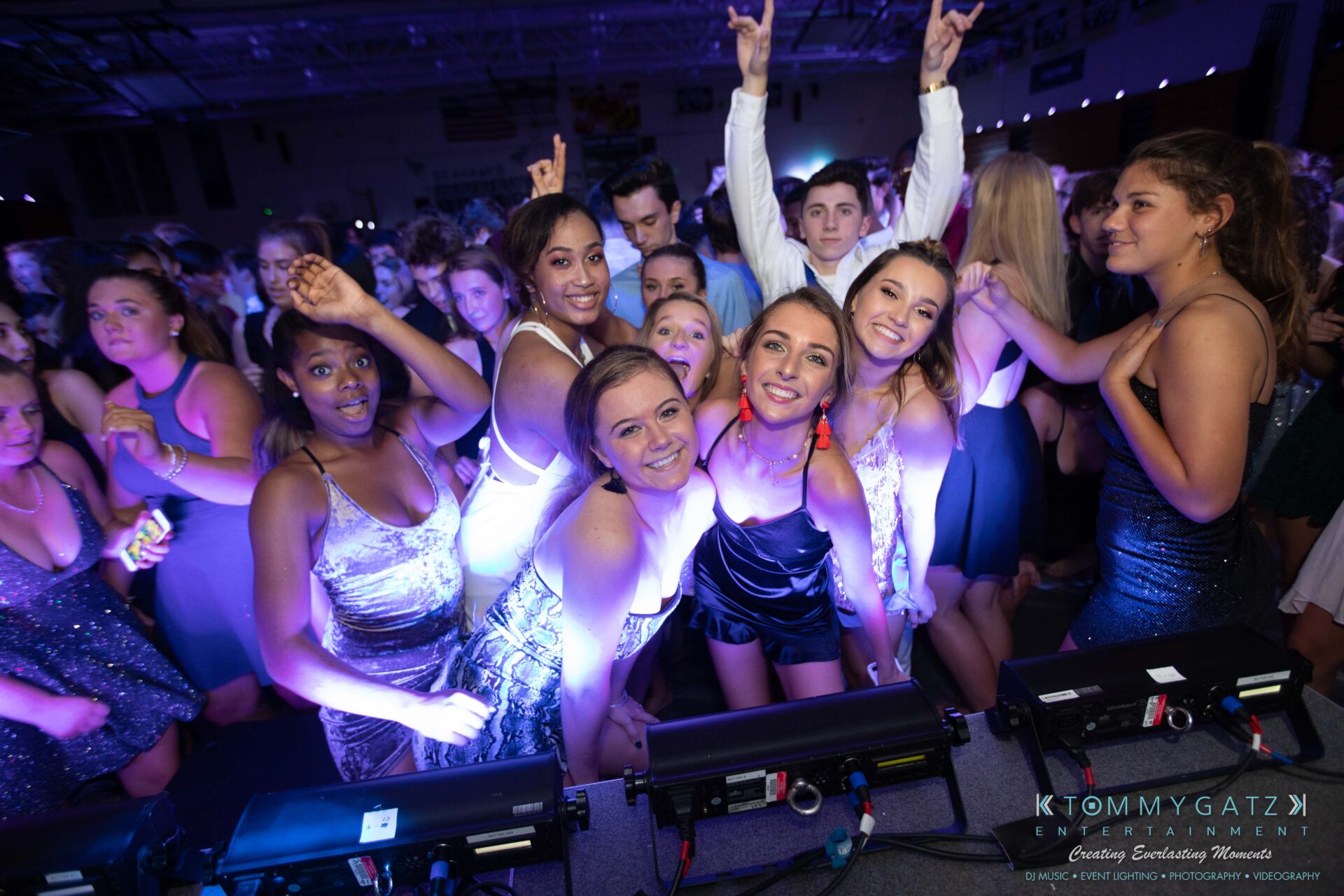 100519-South-River-HC-Dance-Low-Res-WM-79 - TOMMY GATZ ENTERTAINMENT A group of young people in formal attire pose and smile for a photo at a lively indoor event.