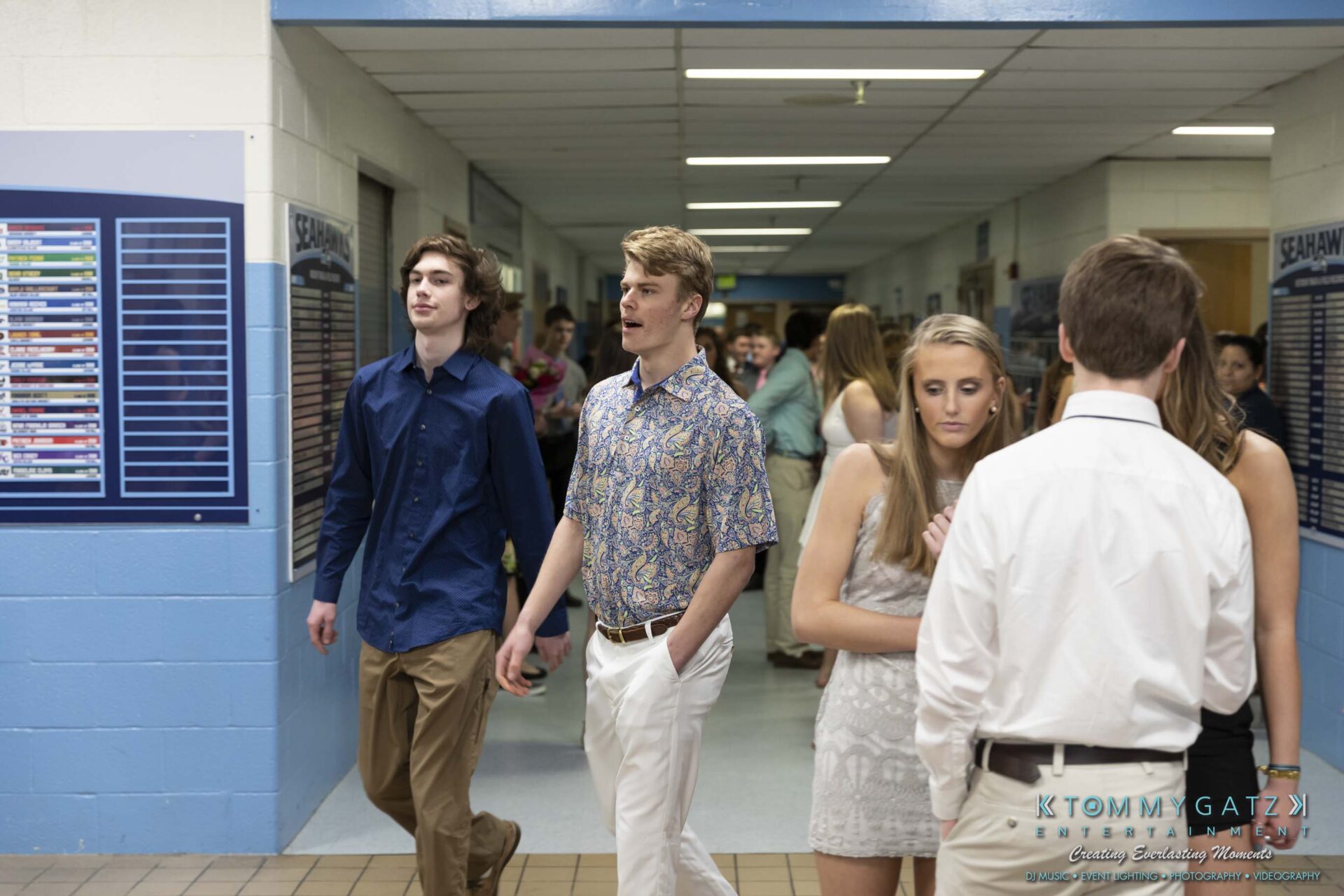SR-Spring-Fling-032319-FINALS-Low-Res-WM-15 - TOMMY GATZ ENTERTAINMENT A group of young people in semi-formal attire walk through a school hallway with a crowd in the background.