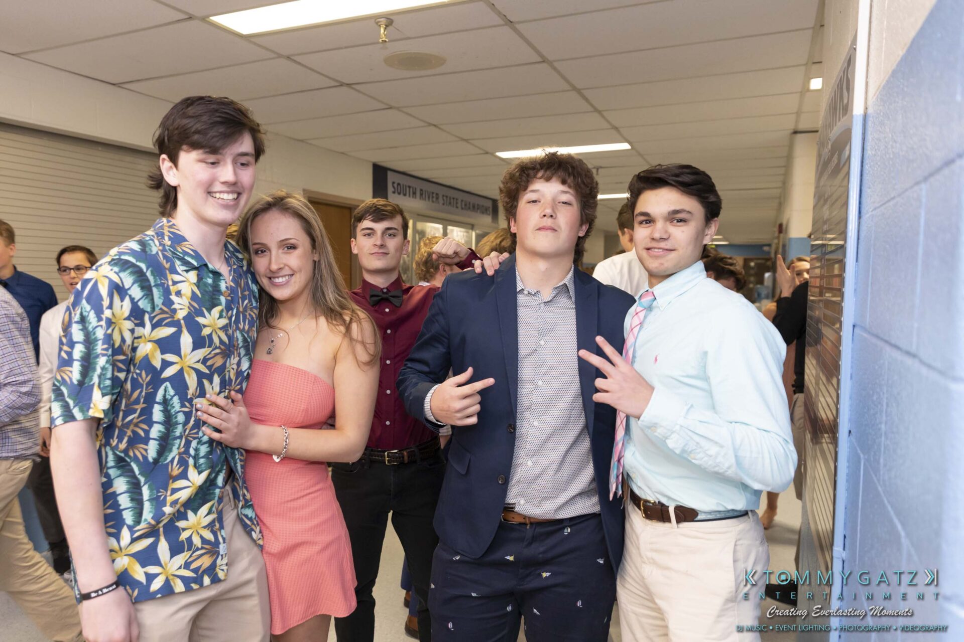 SR-Spring-Fling-032319-FINALS-Low-Res-WM-21 - TOMMY GATZ ENTERTAINMENT A group of young people smiling and posing together in a hallway. They are dressed in semi-formal attire.
