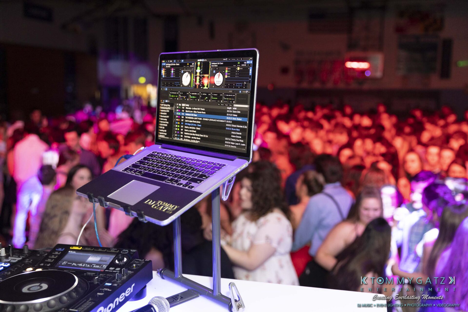 SR-Spring-Fling-032319-FINALS-Low-Res-WM-32 - TOMMY GATZ ENTERTAINMENT Laptop with DJ software on a stand, overlooking a crowded dance floor with people dancing and colorful lights in a dimly lit room.