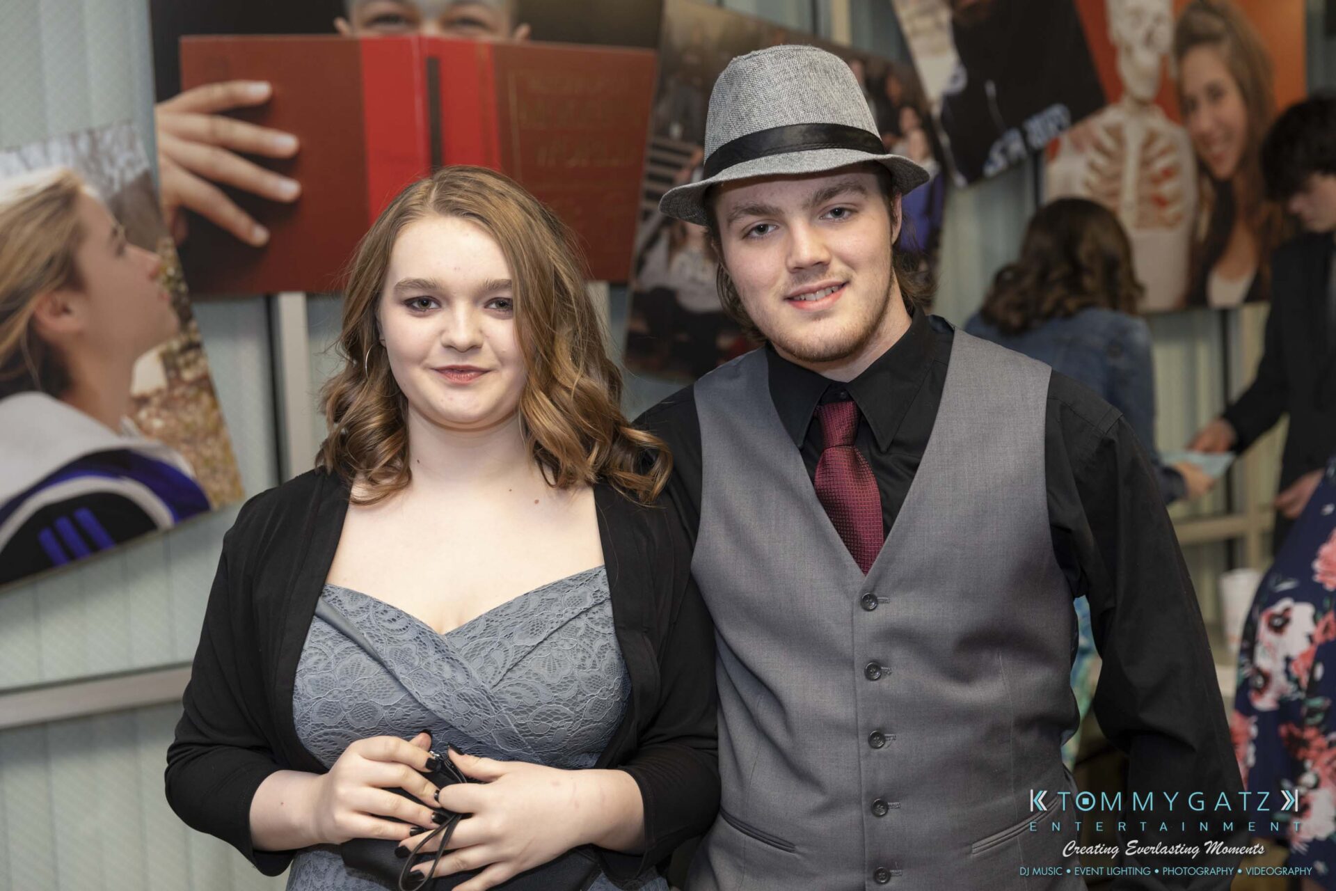 SR-Spring-Fling-032319-FINALS-Low-Res-WM-6 - TOMMY GATZ ENTERTAINMENT Two people dressed formally, with the man wearing a hat and vest, posing together in a room with various photos on the walls.