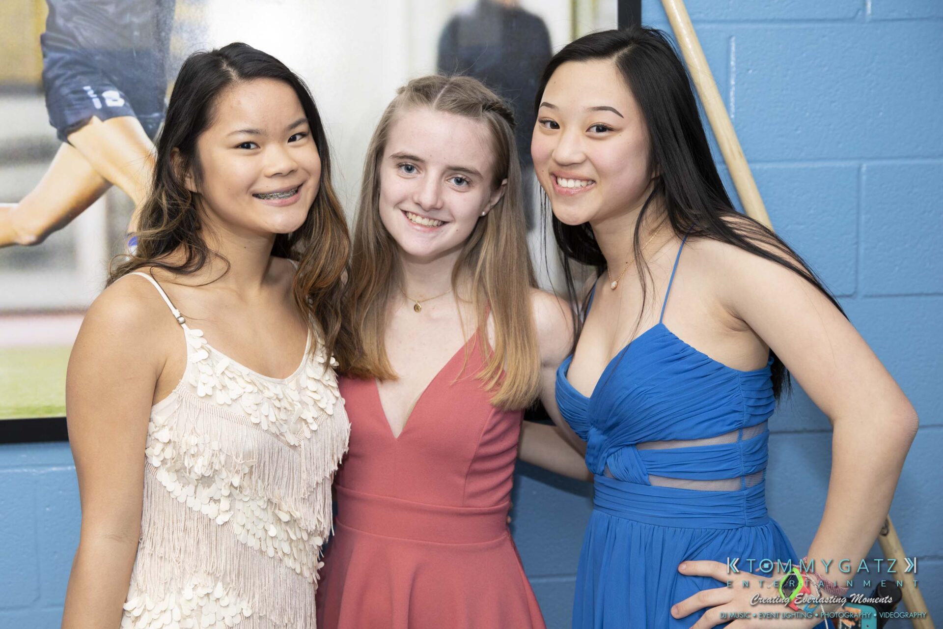 SR-Spring-Fling-032319-FINALS-Low-Res-WM-8 - TOMMY GATZ ENTERTAINMENT Three young women smiling, dressed in formal attire, standing close together in front of a wall display.