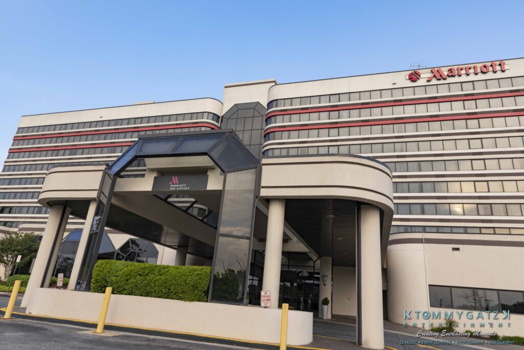 Front view of a large hotel building with "Marriott" signage, featuring an entrance with a covered driveway and multiple stories of windows above.