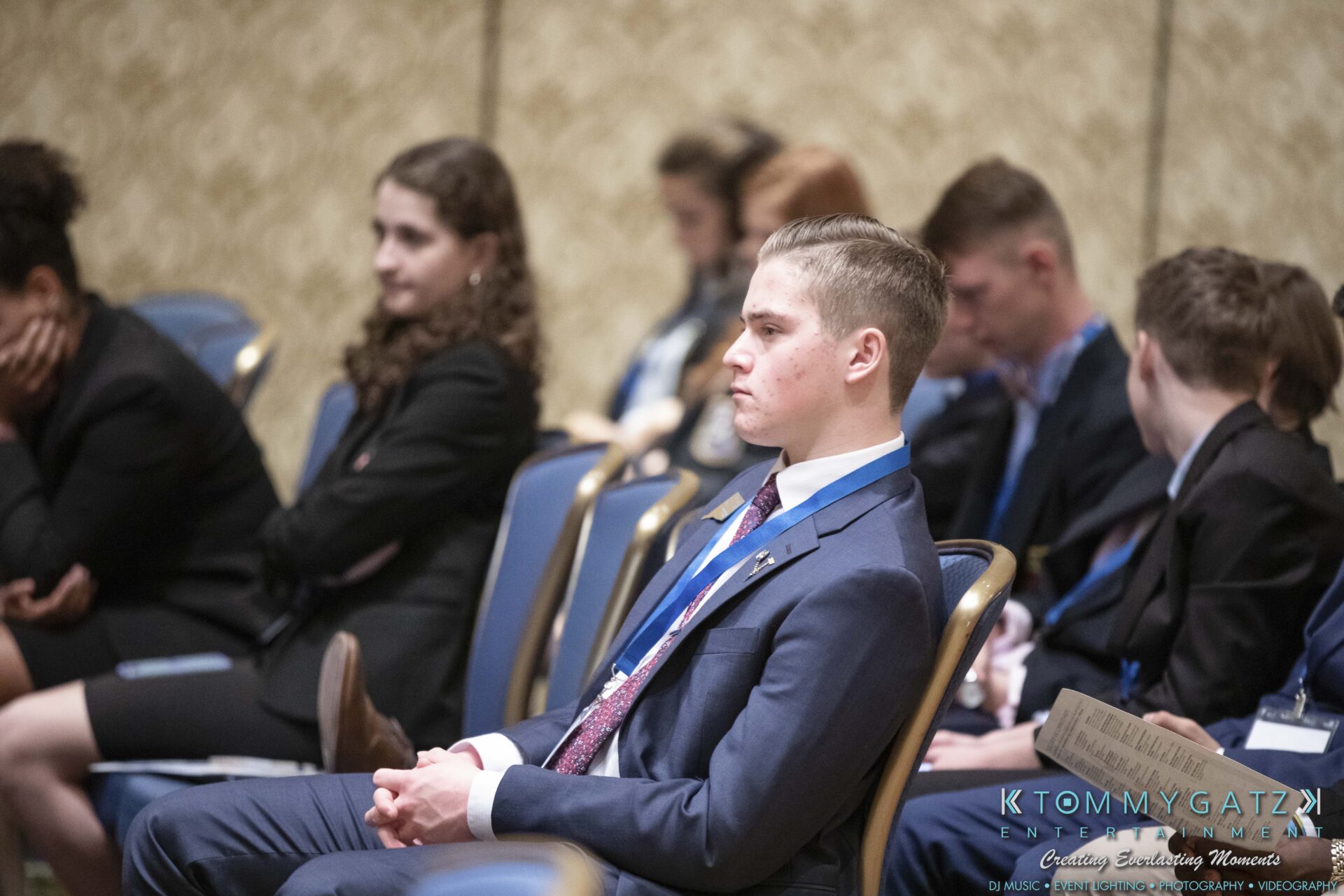 DECA-2018-Low-Res-WM-14 - TOMMY GATZ ENTERTAINMENT Group of people in formal attire sitting in a conference room, facing forward.