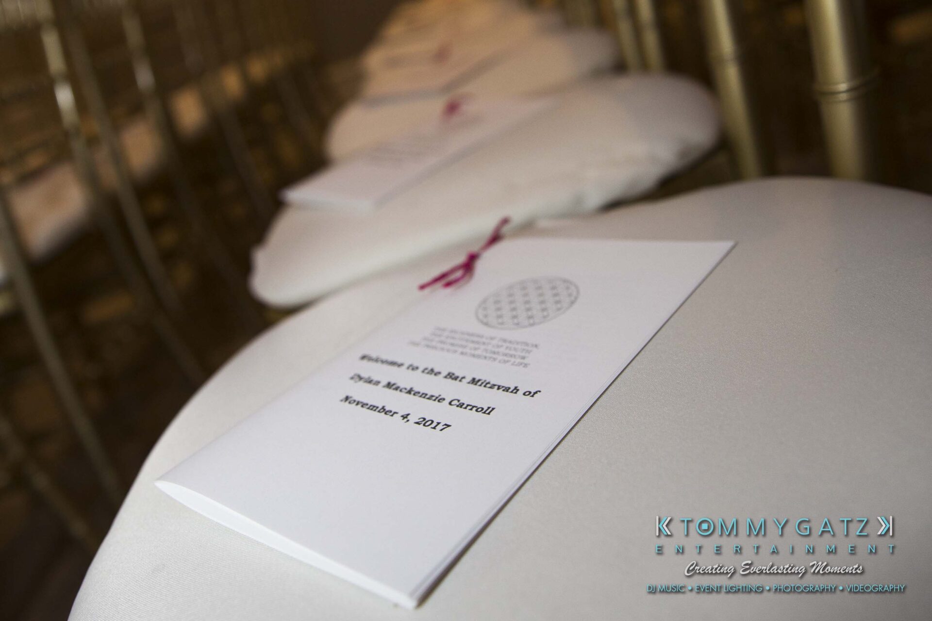 Dylans-Bat-Mitzvah-CEREMONY-Low-Res-WM-2 - TOMMY GATZ ENTERTAINMENT Rows of chairs with white programs placed on each seat, titled "Br. Mitzvah of Dylan Mackenzie Curtis" dated November 4, 2017.