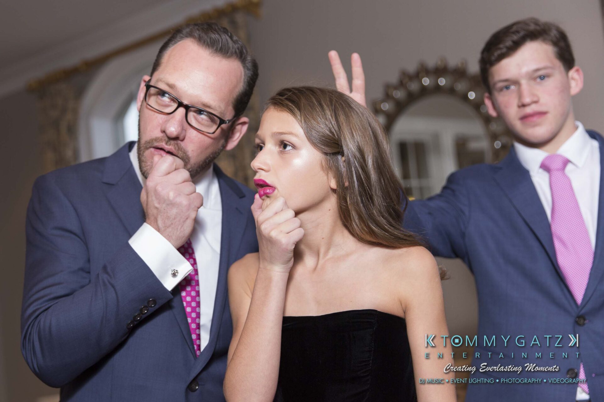 Dylans-Bat-Mitzvah-PORTRAITS-Low-Res-WM-31 - TOMMY GATZ ENTERTAINMENT Three people posing playfully; two in formal attire mimic thinking, while the third in the background makes a funny gesture.