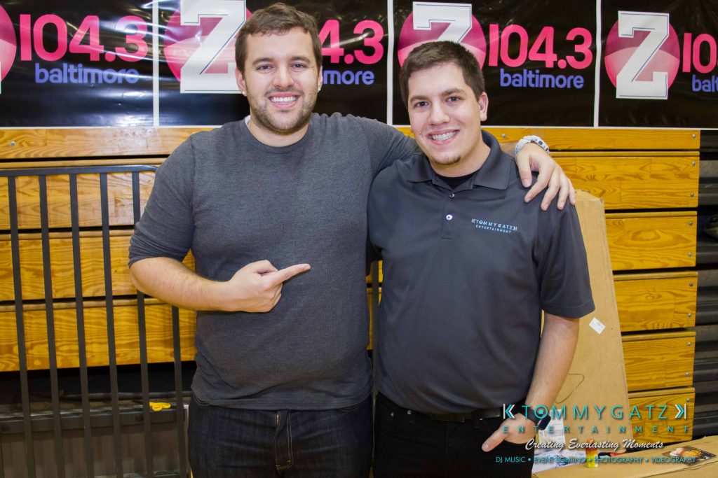 Ford-Driving-Skills-For-Life-52-1024x683 - TOMMY GATZ ENTERTAINMENT Two people standing side by side, smiling at the camera, in front of a backdrop with "Z 104.3 Baltimore" branding.