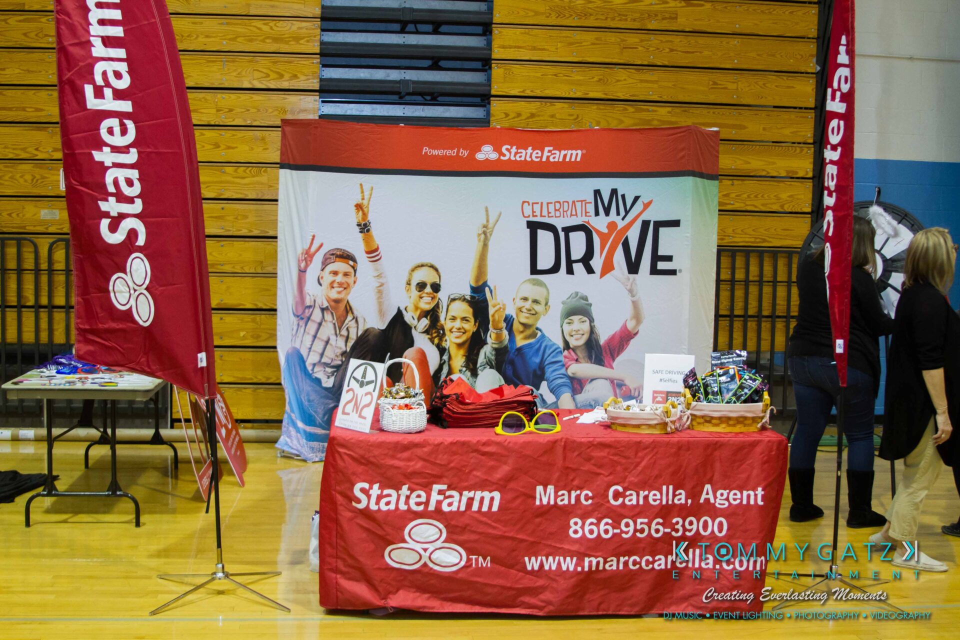 Ford-Driving-Skills-For-Life-55 - TOMMY GATZ ENTERTAINMENT State Farm booth with "Celebrate My Drive" banner, promotional materials, and contact info for agent Marc Carella.