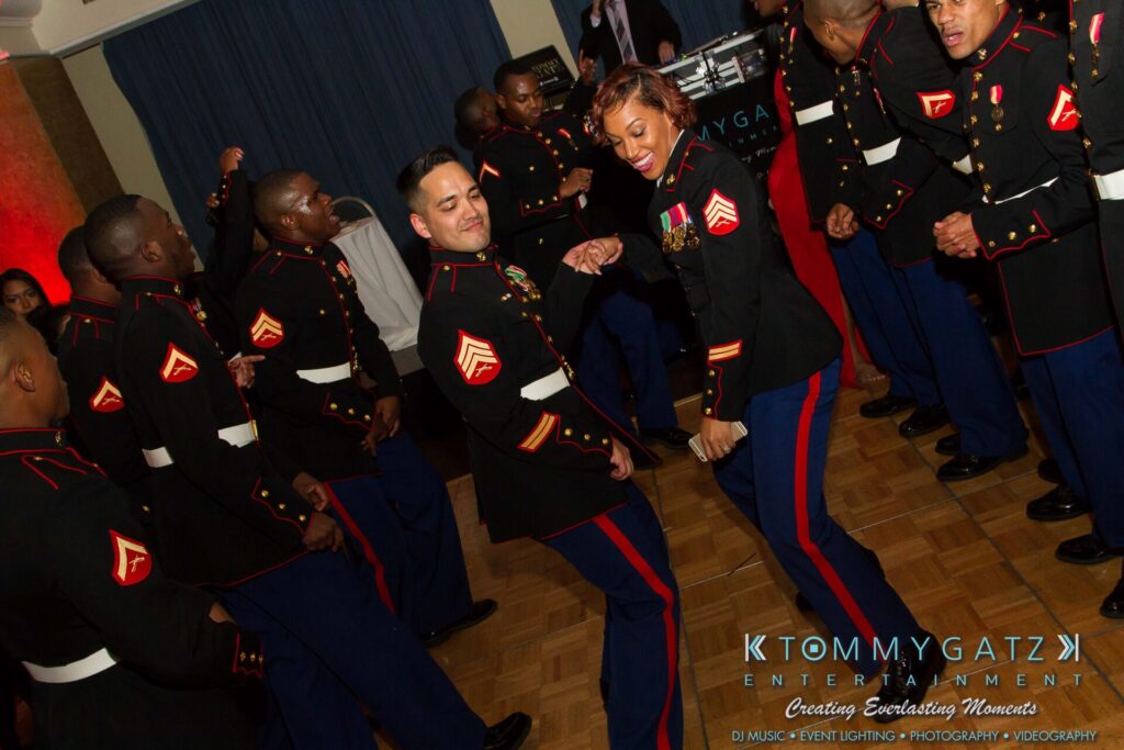 Marine-Lo-Res-163 - TOMMY GATZ ENTERTAINMENT Marines in dress uniforms dance and enjoy themselves at an event on a wooden floor.