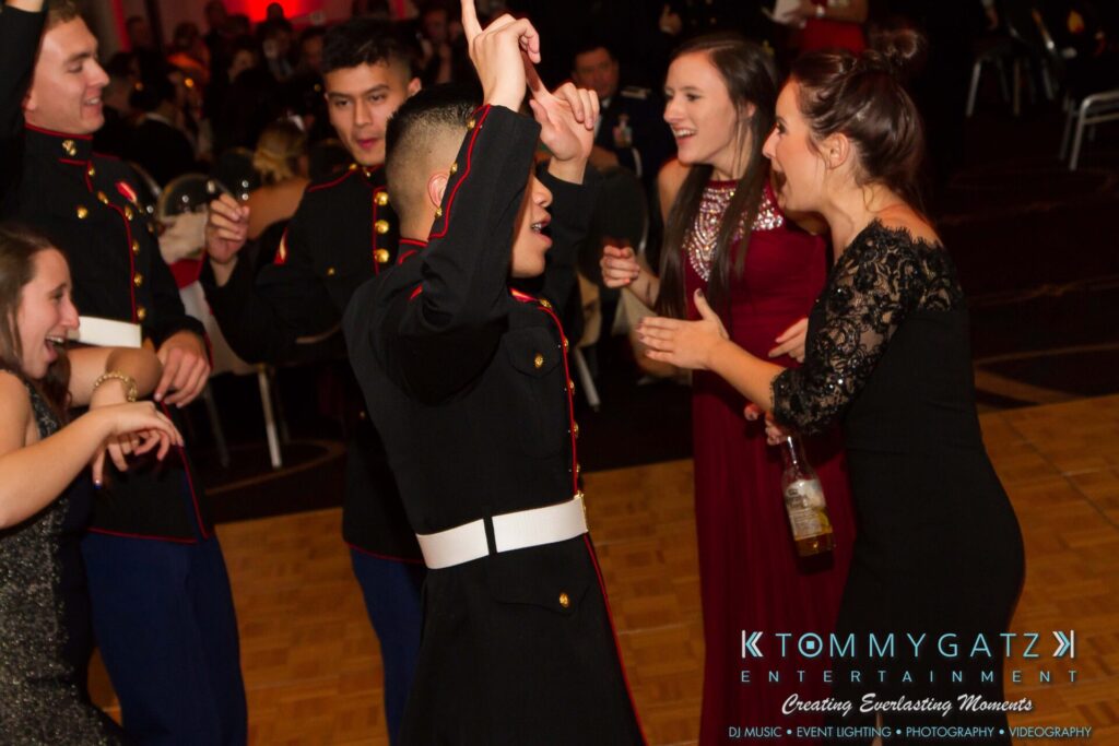 Marine-Lo-Res-65 - TOMMY GATZ ENTERTAINMENT A group of people in formal attire, including military uniforms, are dancing and socializing at an event.