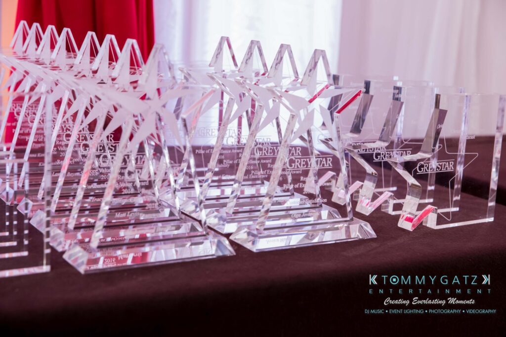Pillar-Awards-32417-ADDITIONS-Blog-WM-7 - TOMMY GATZ ENTERTAINMENT A collection of star-shaped glass awards on a table, displaying the Greystar logo.