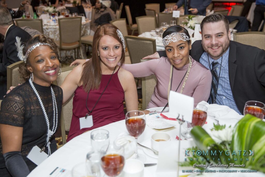 Pillar-Awards-Final-3-24-17-Blog-WM-290 - TOMMY GATZ ENTERTAINMENT Four people seated at a round table with drinks and nametags, smiling for the camera in a banquet setting.