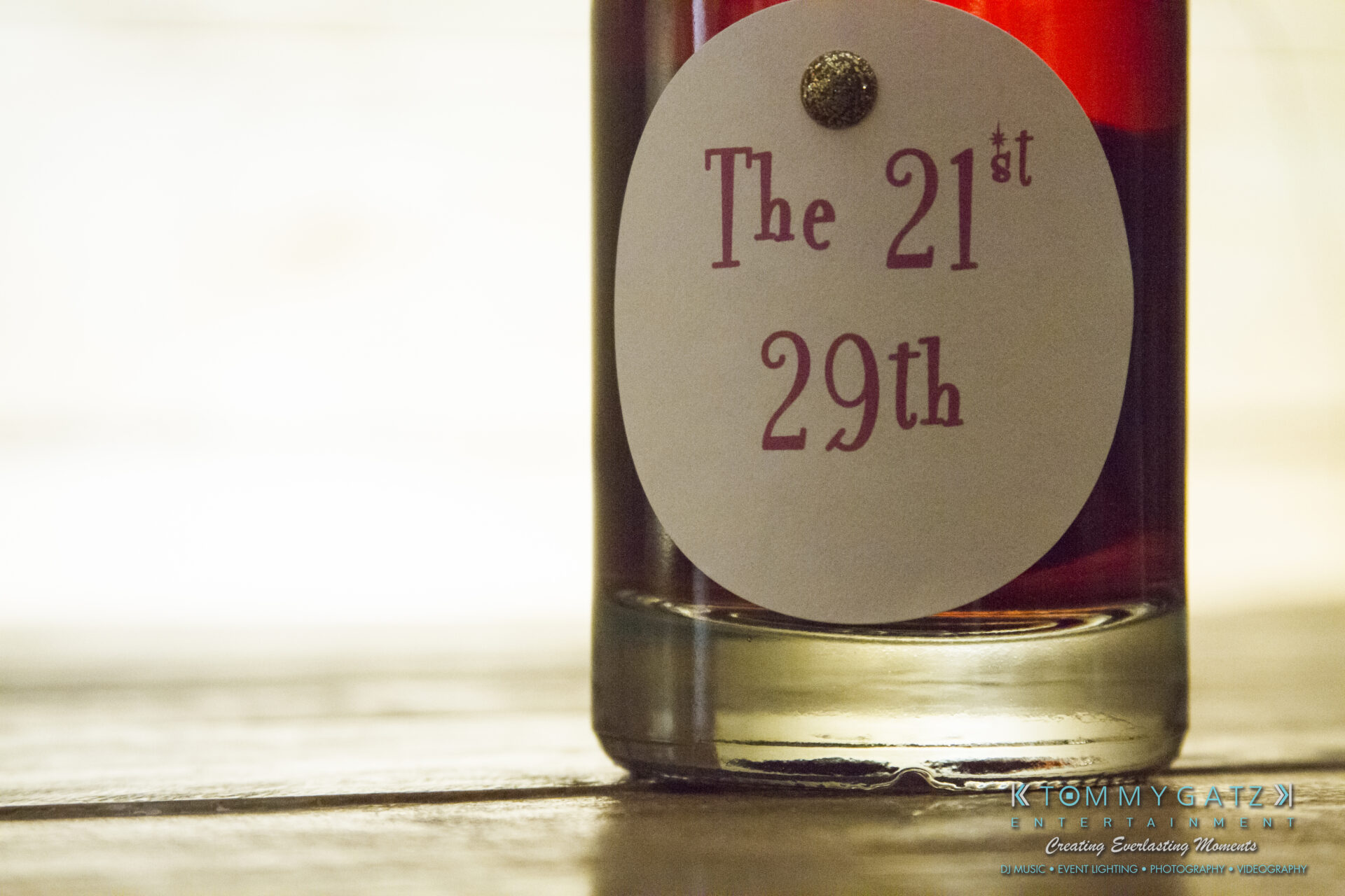 SUSAN_50TH_BIRTHDAY_WATERMARK12 - TOMMY GATZ ENTERTAINMENT Close-up of a glass bottle with a white label reading "The 21st 29th" in red text.