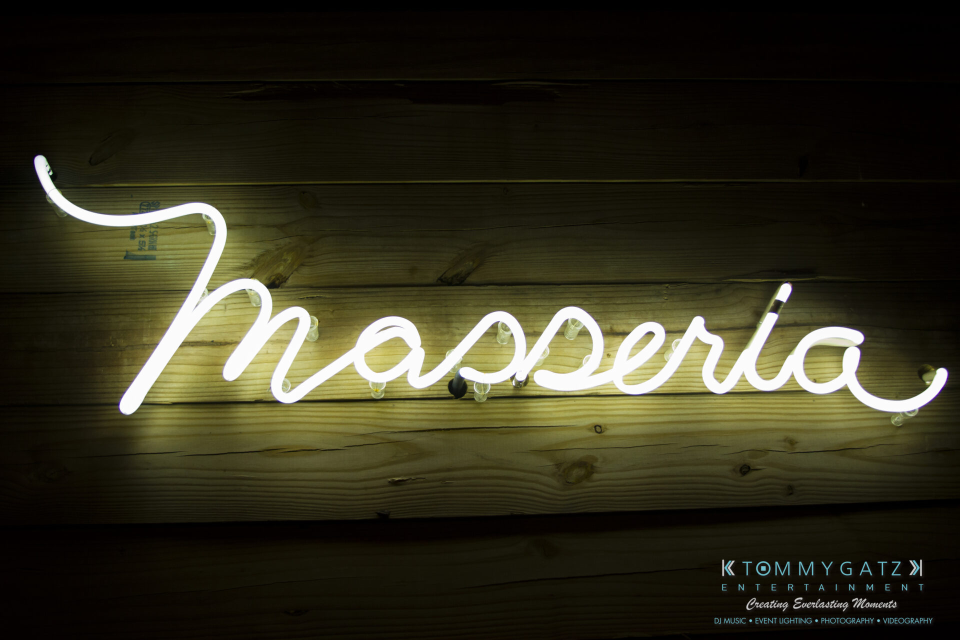SUSAN_50TH_BIRTHDAY_WATERMARK39 - TOMMY GATZ ENTERTAINMENT White neon sign reading "Masseria" on a wooden wall background.