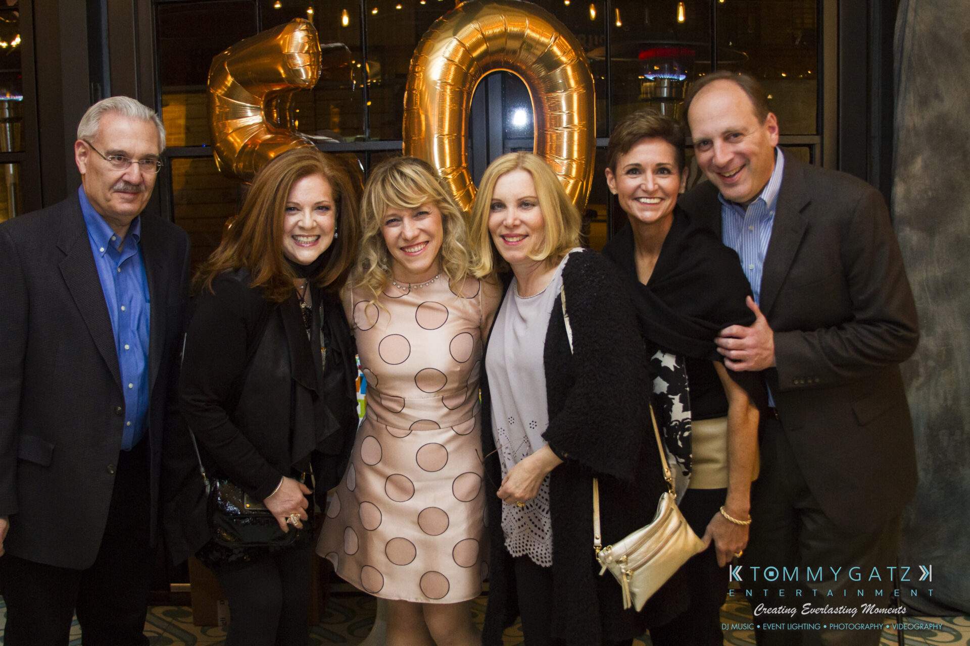 SUSAN_50TH_BIRTHDAY_WATERMARK52 - TOMMY GATZ ENTERTAINMENT Six people posing together at a party with a large "50" balloon in the background.