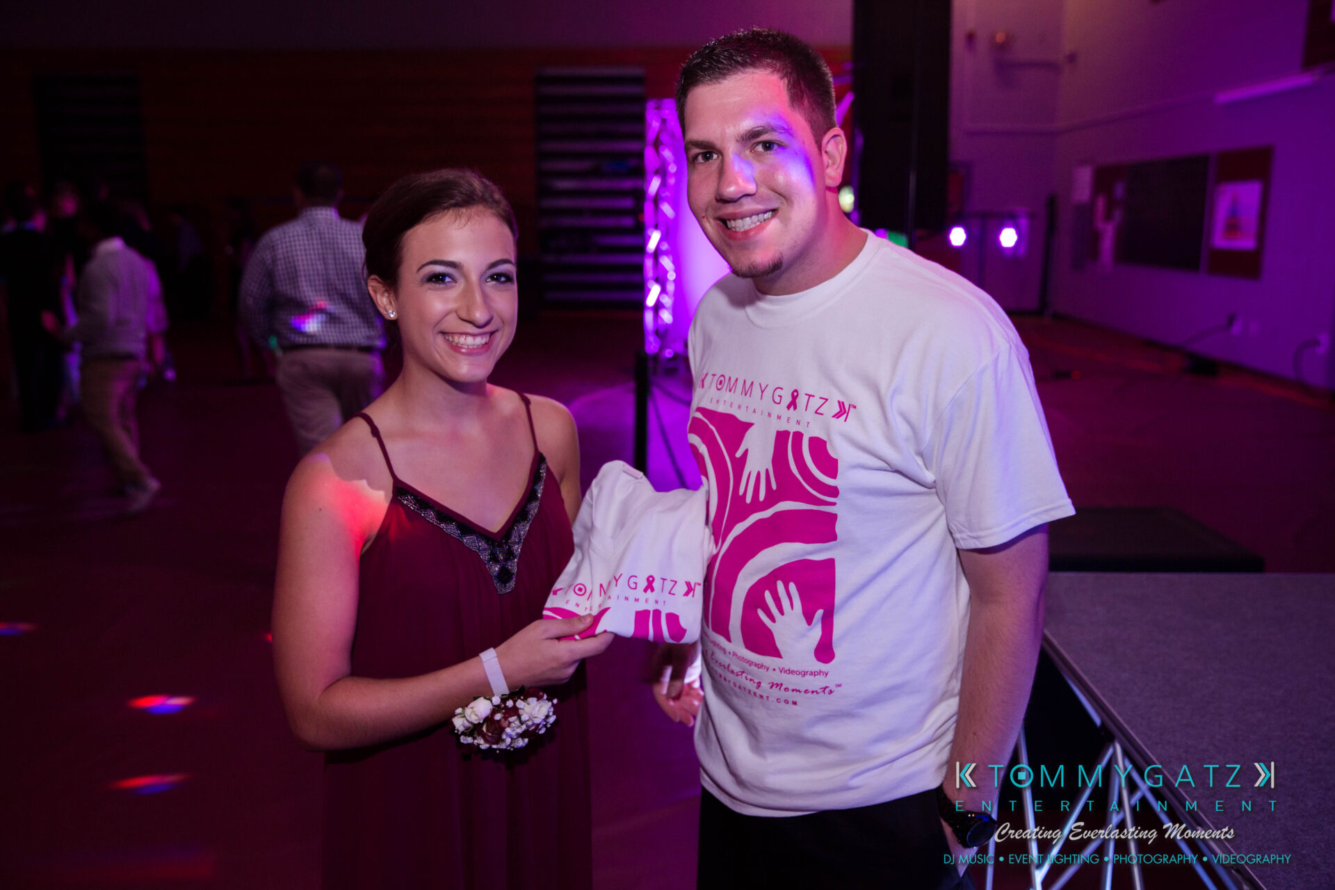 untitled-25 - TOMMY GATZ ENTERTAINMENT A man and woman smiling indoors at an event. The woman holds a white shirt.