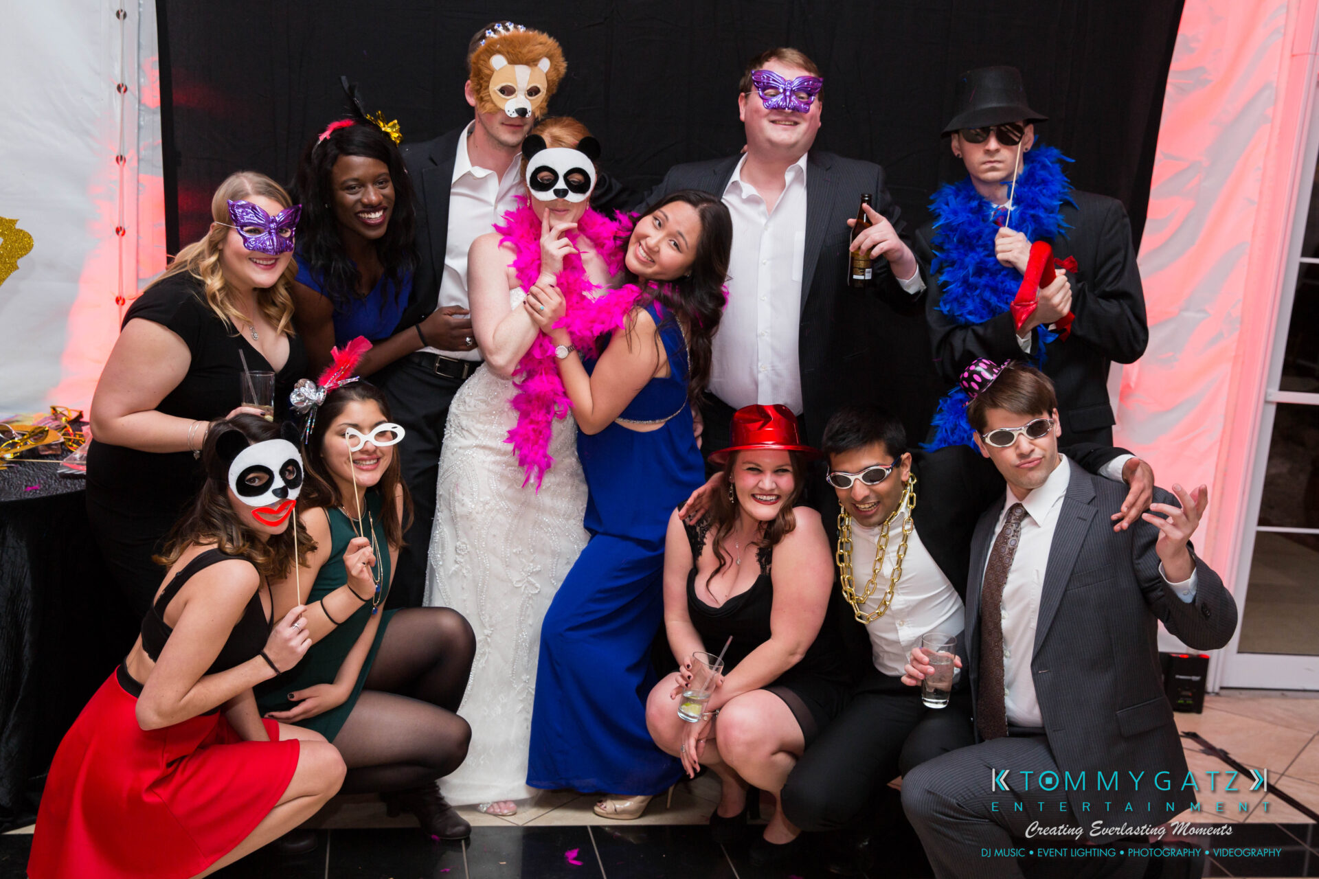 untitled-38 - TOMMY GATZ ENTERTAINMENT A group of people wearing colorful masks and costumes pose together at an indoor event.