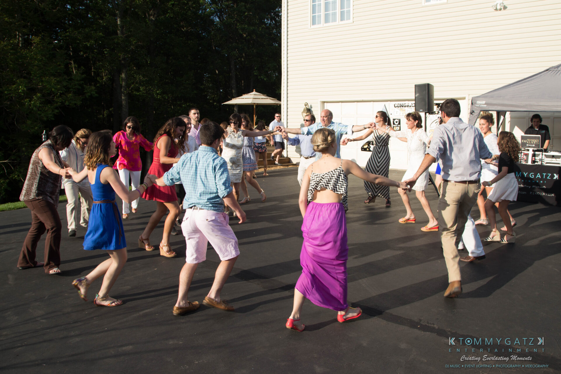 untitled-40 - TOMMY GATZ ENTERTAINMENT A group of people holding hands and dancing in a circle outdoors at a gathering.