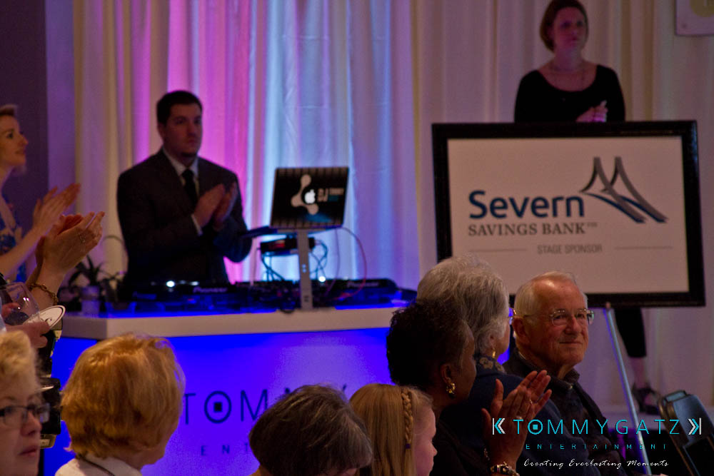 untitled-46 - TOMMY GATZ ENTERTAINMENT People clapping at an indoor event with a DJ and a Severn Savings Bank sign in the background.
