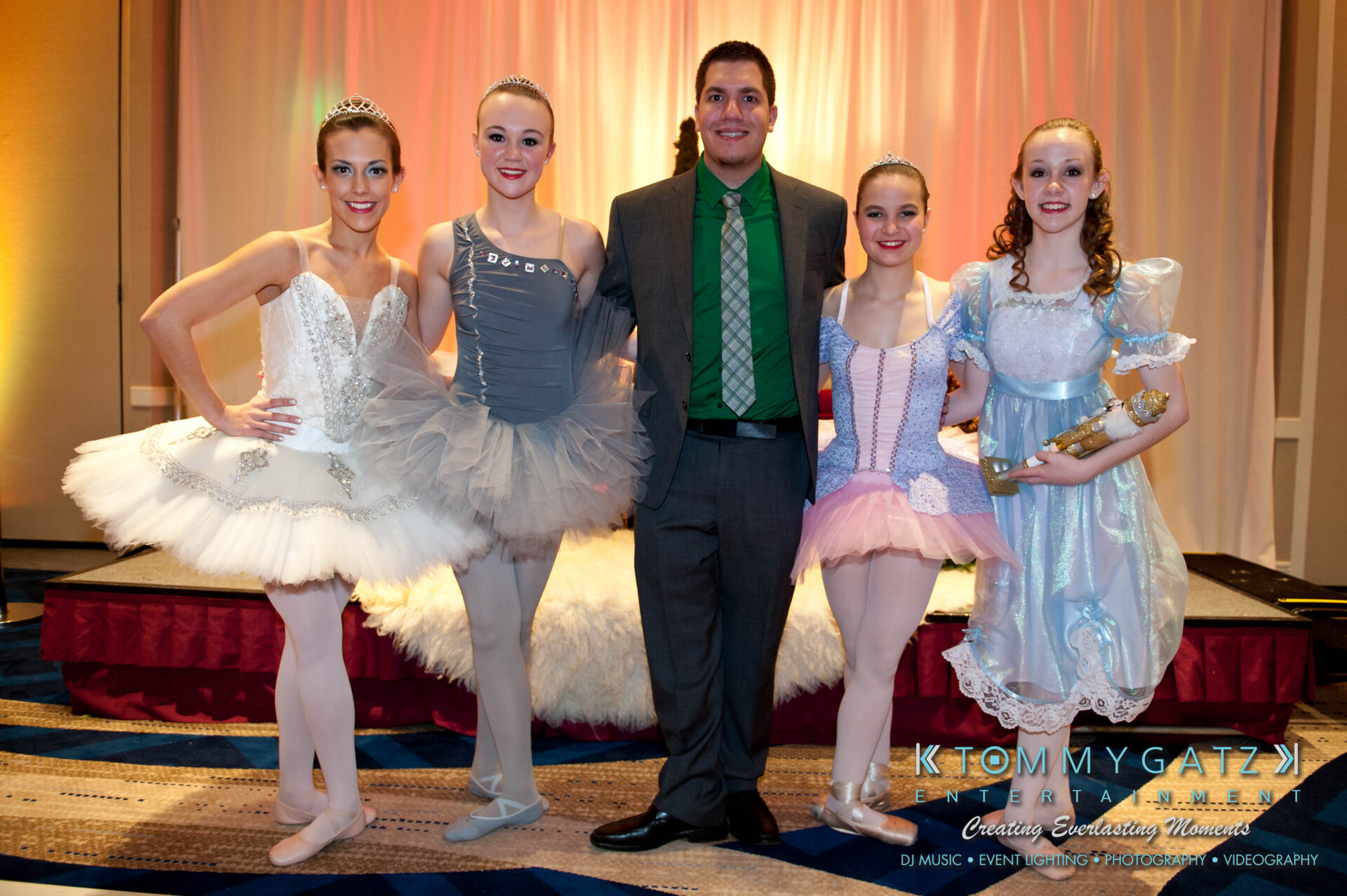 untitled-61 - TOMMY GATZ ENTERTAINMENT A group of people posing on stage, including one man in a suit and four women dressed in ballet costumes.