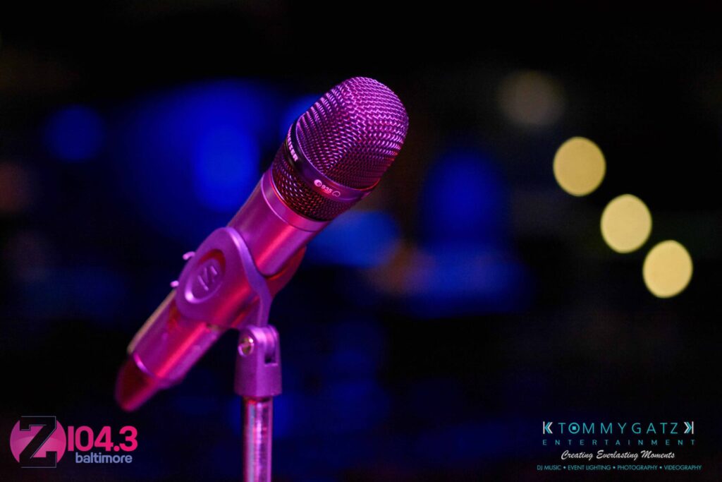 Intern-John-Peer-Pressure-Comedy-Show-Baltimore-7-14-17-Blog-Watermark-2 - TOMMY GATZ ENTERTAINMENT A microphone on a stand with blurred lights in the background. Logos for Z104.3 Baltimore and Tommy Gatz Entertainment are visible.