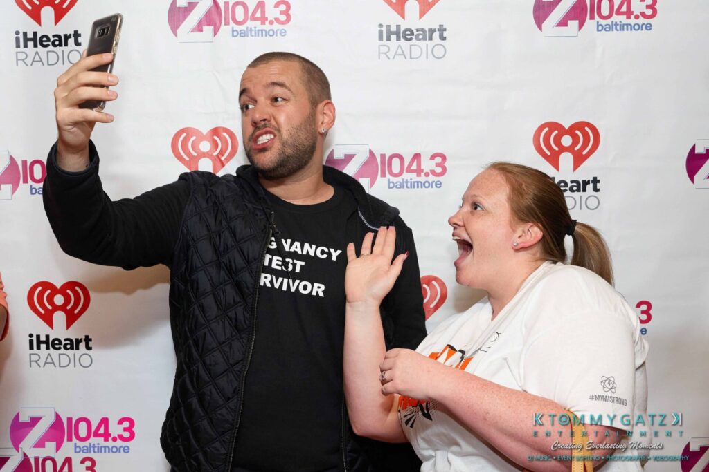 Intern-John-Peer-Pressure-Comedy-Show-Baltimore-7-14-17-Blog-Watermark-44 - TOMMY GATZ ENTERTAINMENT Two people taking a selfie in front of a backdrop with radio station logos.