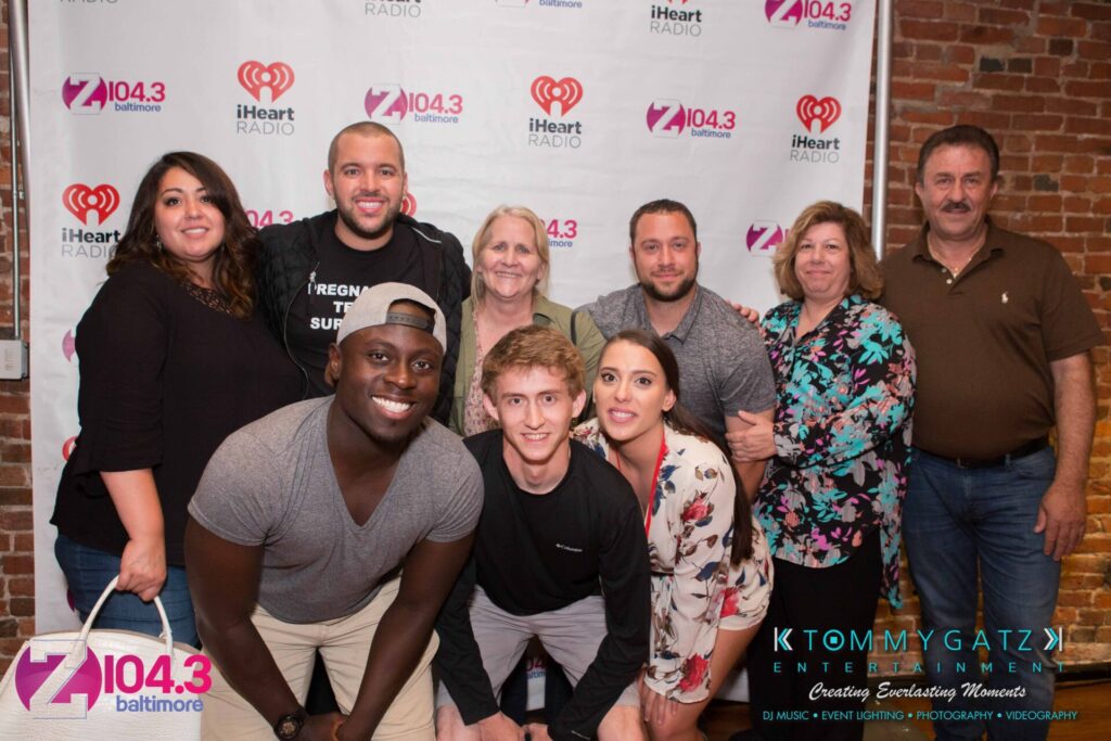 Intern-John-Peer-Pressure-Comedy-Show-Baltimore-7-14-17-Blog-Watermark-46 - TOMMY GATZ ENTERTAINMENT A group of people posing together in front of a step-and-repeat banner with various logos, including a radio station and entertainment company.