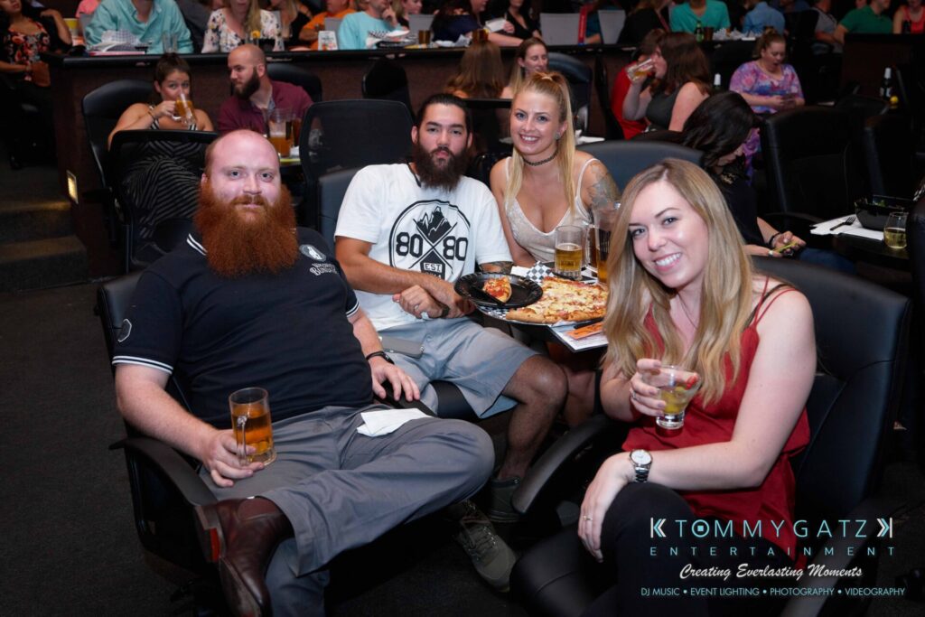 Intern-John-Peer-Pressure-Comedy-Tour-Arlington-7-21-17-low-res-Watermark-38 - TOMMY GATZ ENTERTAINMENT Four people seated at a table, enjoying drinks and food in a lively venue.