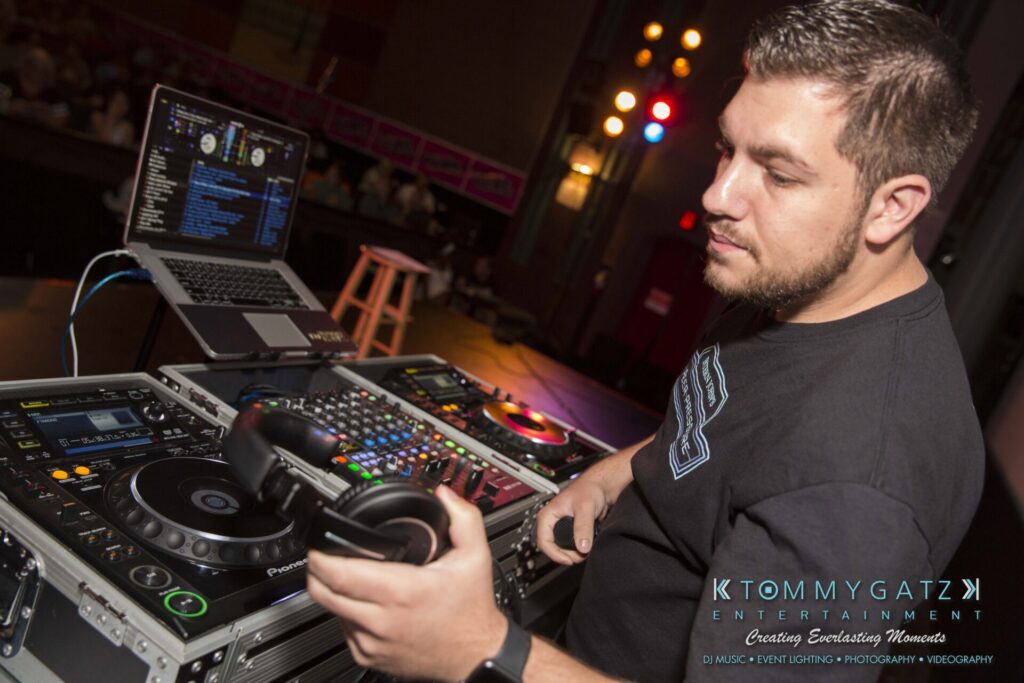 Intern-John-Pressure-Comedy-Tour-ARLINGTON-BLOG-WM-29-of-323 - TOMMY GATZ ENTERTAINMENT DJ at a mixing console adjusting equipment, with a laptop displaying music software in the background.