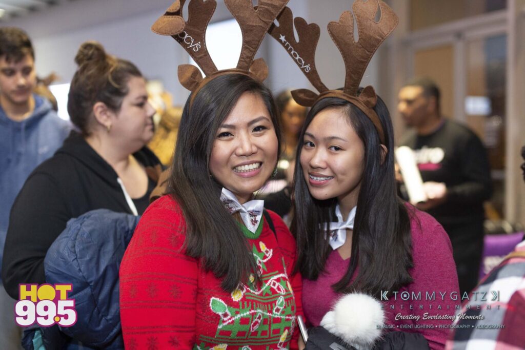 Jingle-Ball-2018-BTS-06 - TOMMY GATZ ENTERTAINMENT Two people wearing reindeer antlers and festive attire smile at an event.