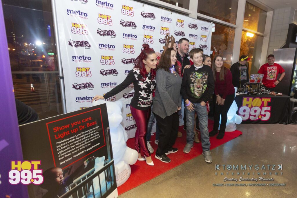 Jingle-Ball-2018-BTS-20 - TOMMY GATZ ENTERTAINMENT Group of people posing on a red carpet at a Hot 99.5 event with promotional signage in the background.