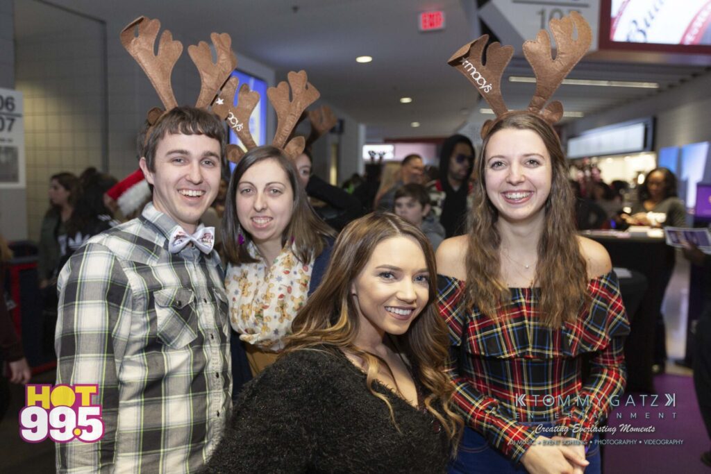 Jingle-Ball-2018-BTS-24 - TOMMY GATZ ENTERTAINMENT A group of four people wearing reindeer antlers poses indoors at an event.