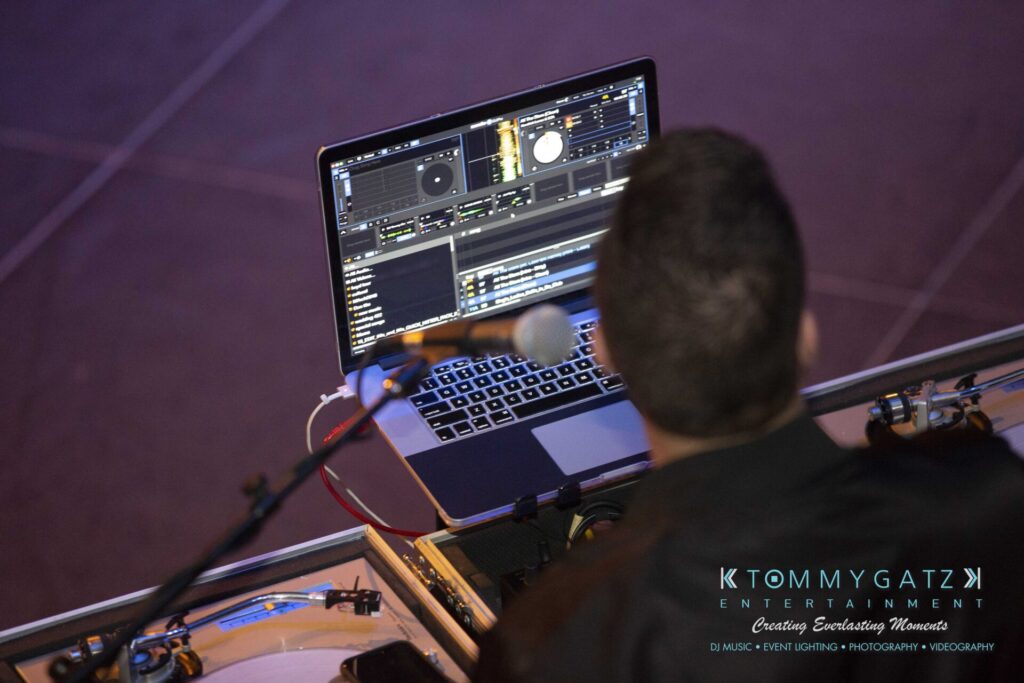 LWYD-Comedy-Tour-Baltimore-060118-FINALS-Low-Res-Watermark-120 - TOMMY GATZ ENTERTAINMENT A DJ is working on a laptop with music software open. Turntables and DJ equipment are visible in the setup.