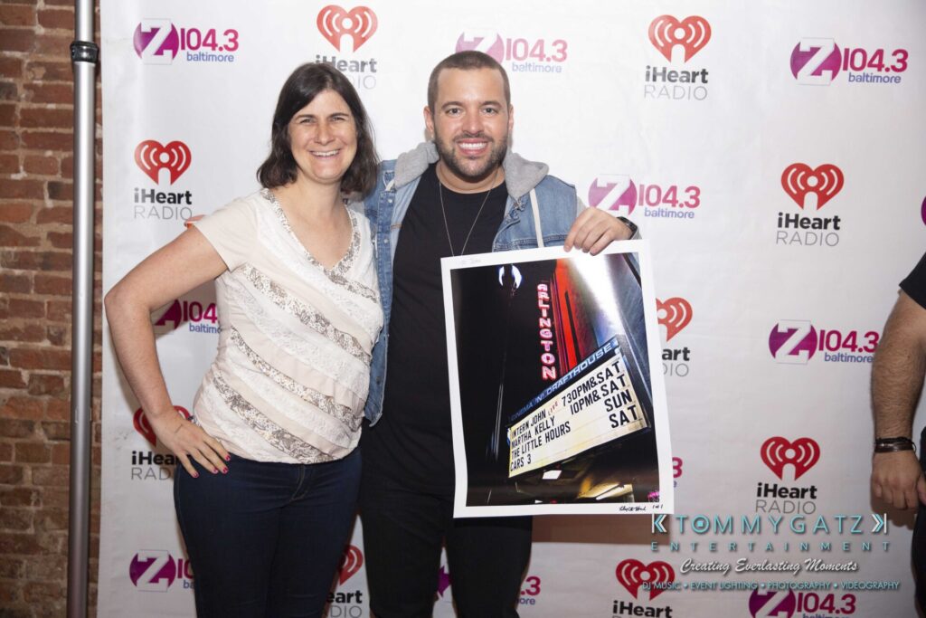 LWYD-Comedy-Tour-Baltimore-060118-FINALS-Low-Res-Watermark-364 - TOMMY GATZ ENTERTAINMENT Two people stand in front of an iHeart Radio backdrop. One is holding a framed photo of a theater marquee.