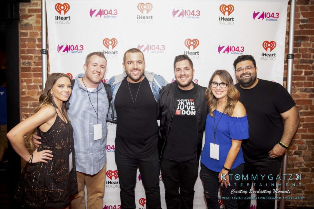LWYD-Comedy-Tour-Baltimore-060118-FINALS-Low-Res-Watermark-419 - TOMMY GATZ ENTERTAINMENT A group of six people posing together in front of a Z104.3 and iHeartRadio backdrop.